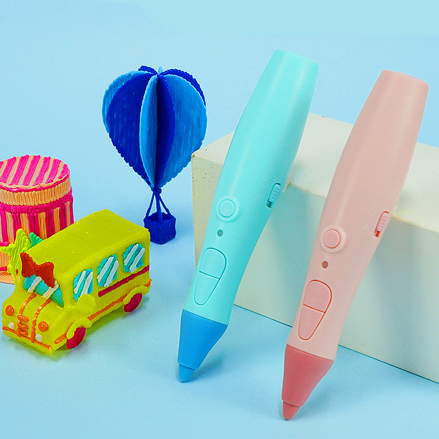 Bunte 3D-Stifte und Modelle: ein grüner Schulbus, ein rosa und blauer Stift und ein Papier-Heißluftballon.