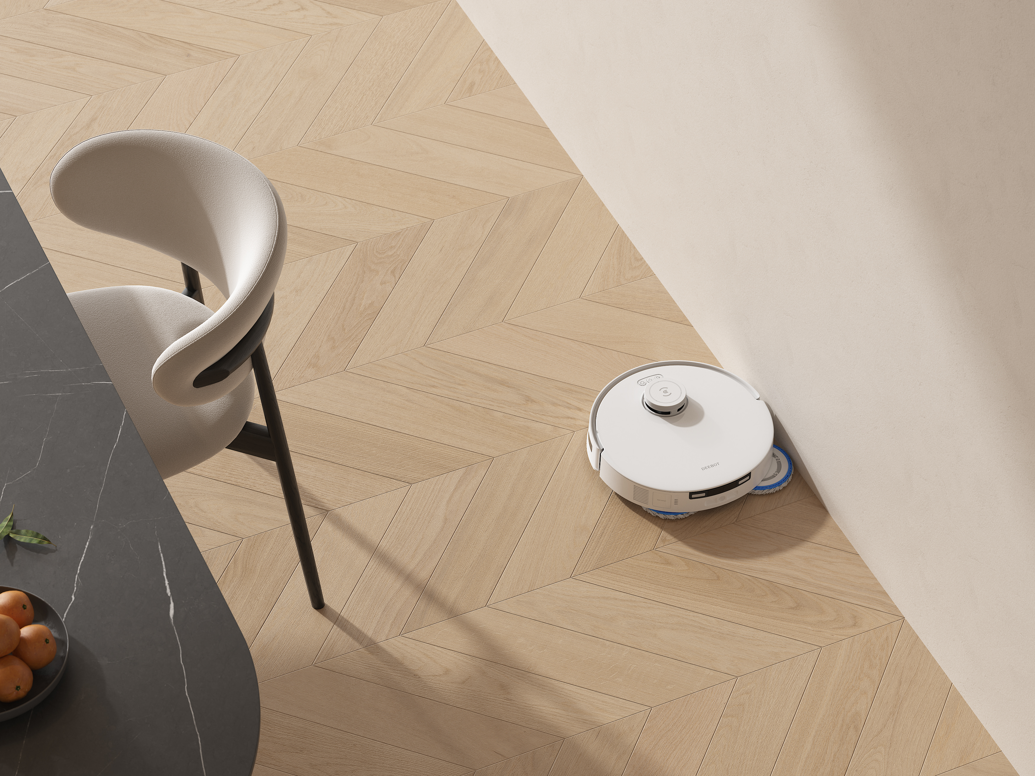 Ein weißer Roboter-Staubsauger auf einem Holzboden. Ein Stuhl und ein Tisch mit Orangen sind im Bild.