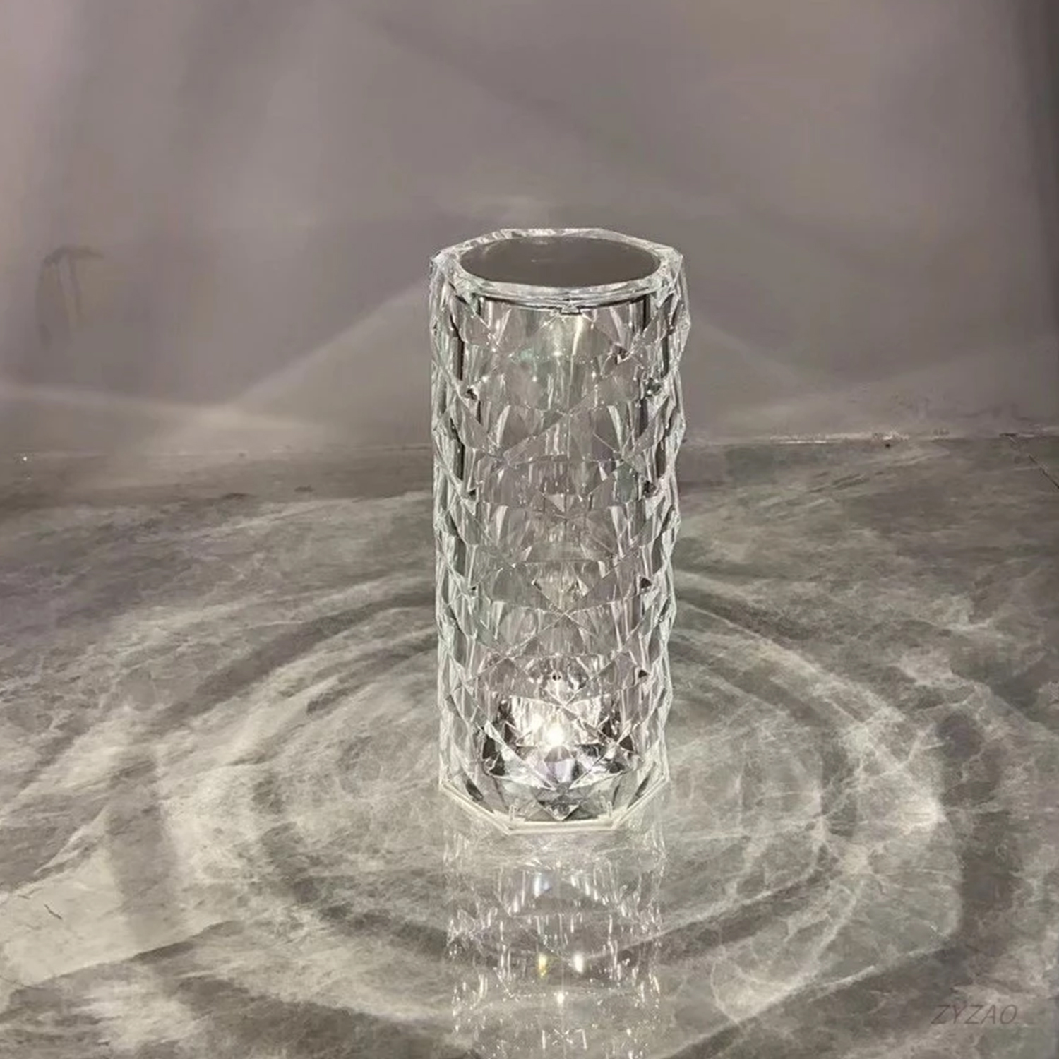 Una lampada a cristallo è illuminata, mostrando le sue sfaccettature su uno sfondo grigio.
