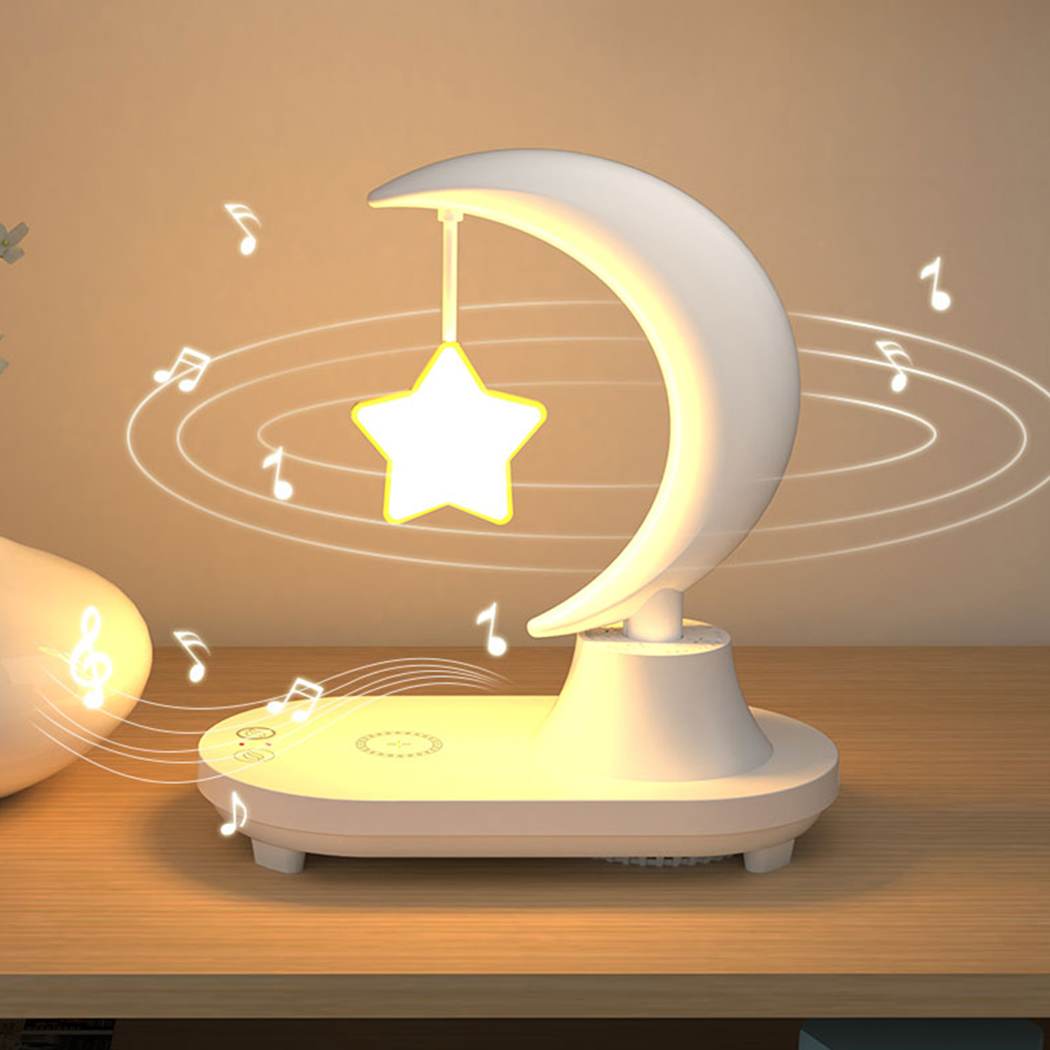 Lampada bianca a forma di mezzaluna con stella sospesa e note musicali, su una superficie di legno.