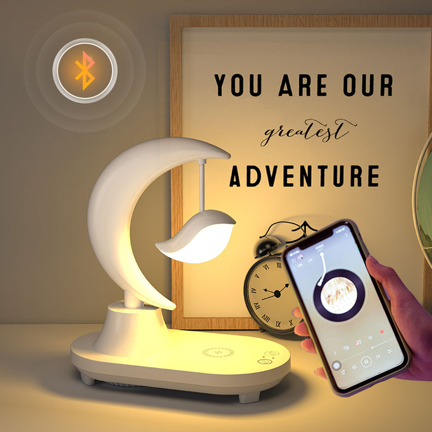 Lampada a forma di luna, telefono e orologio su un tavolo con un messaggio motivazionale.