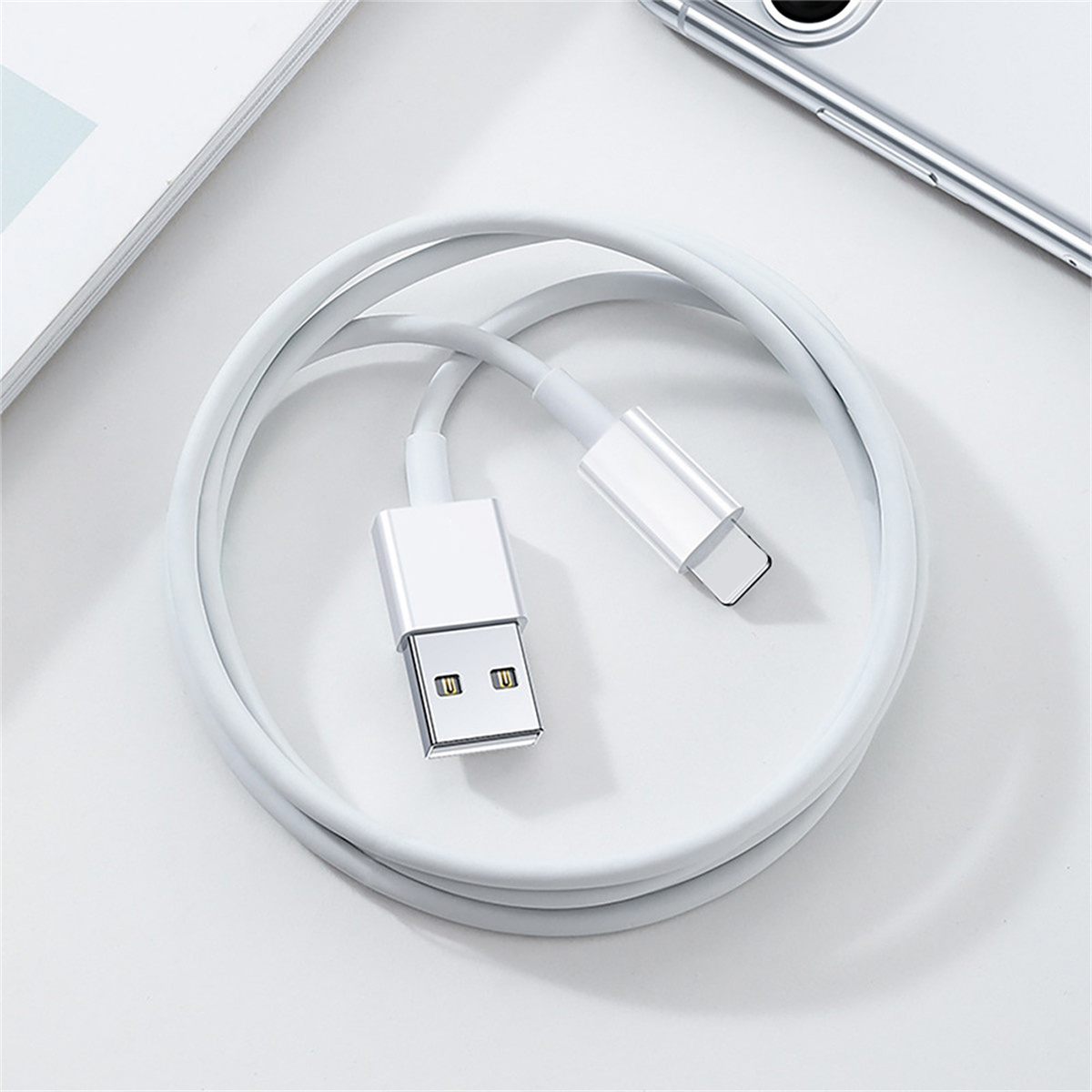 Ein weißes USB-zu-USB-C-Kabel, auf einer weißen Oberfläche gerollt. Nahaufnahme.