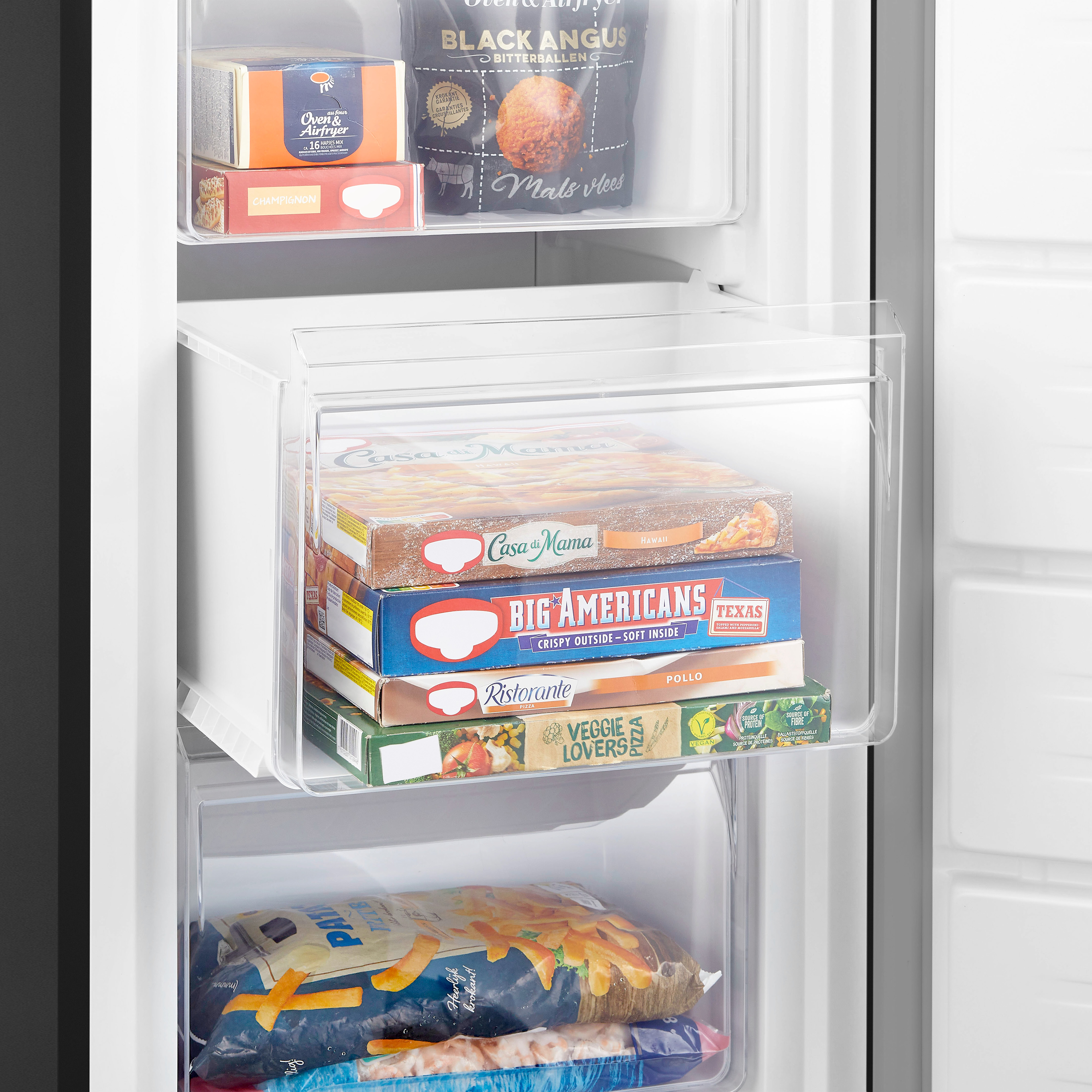 Freezer drawer with frozen food. Contains multiple boxes of pizza and other frozen meals. White interior.