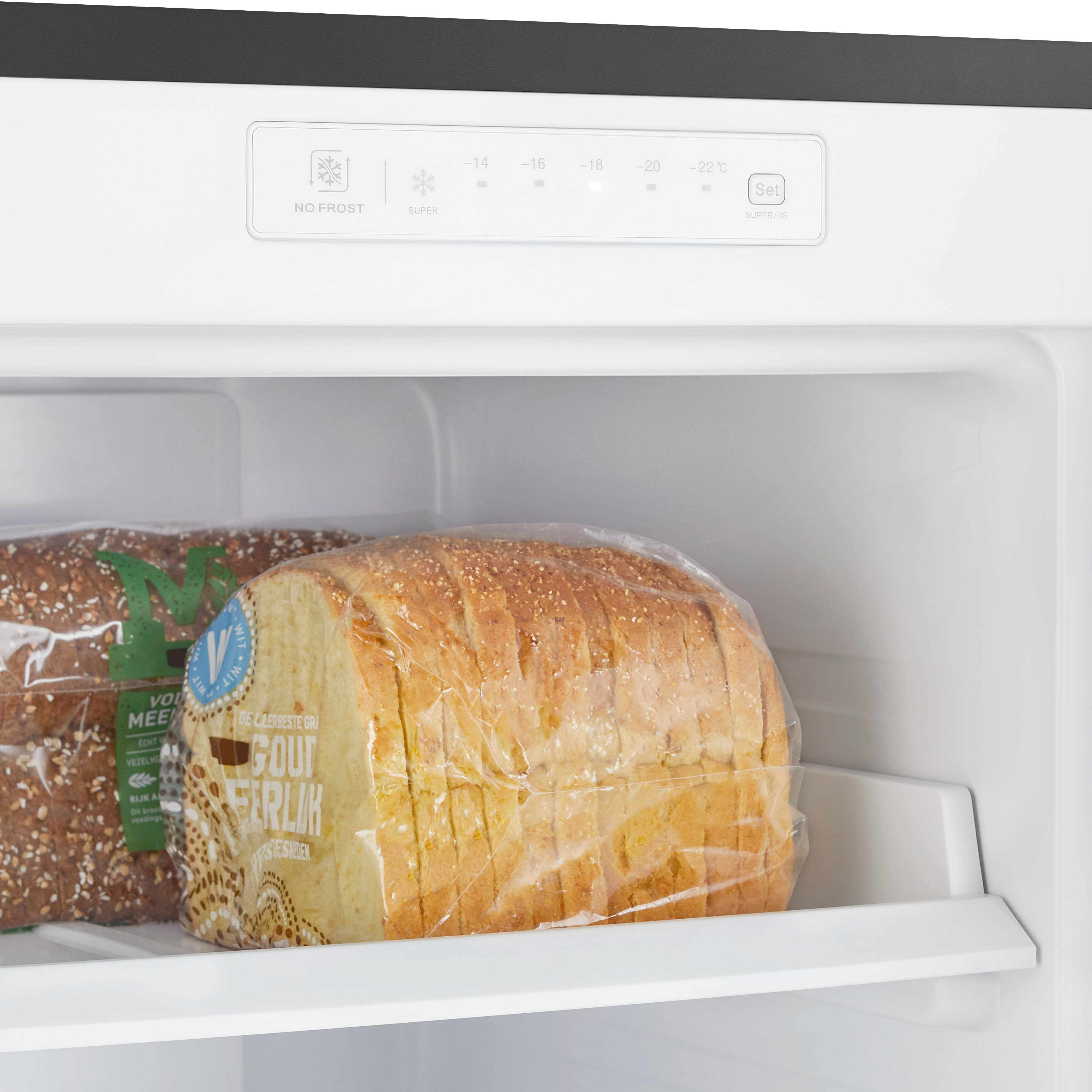 Inside a freezer. There are two loaves of bread and a control panel. The bread is in plastic wrap.