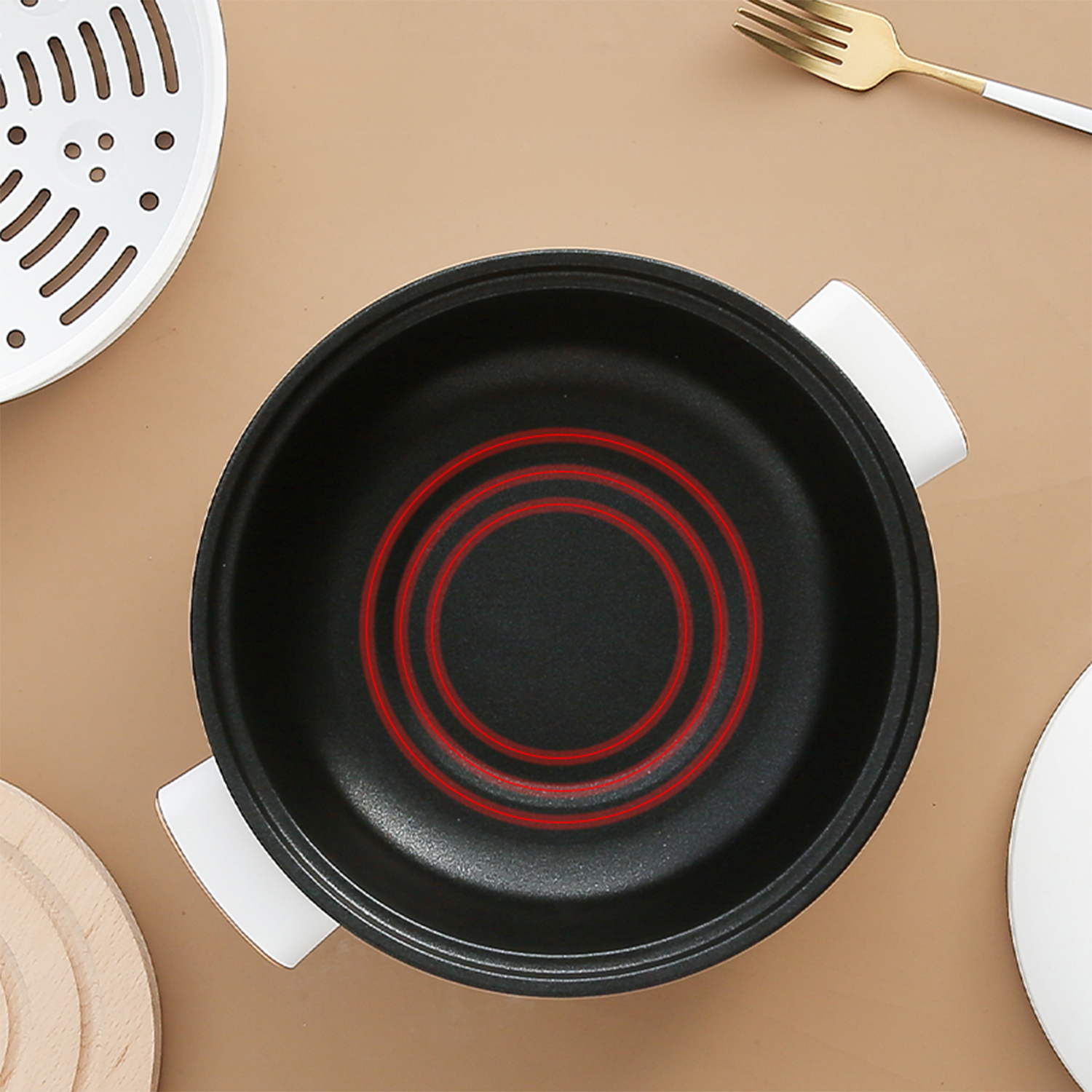 Vista superior de una olla negra con un diseño de elemento calefactor rojo en su interior.