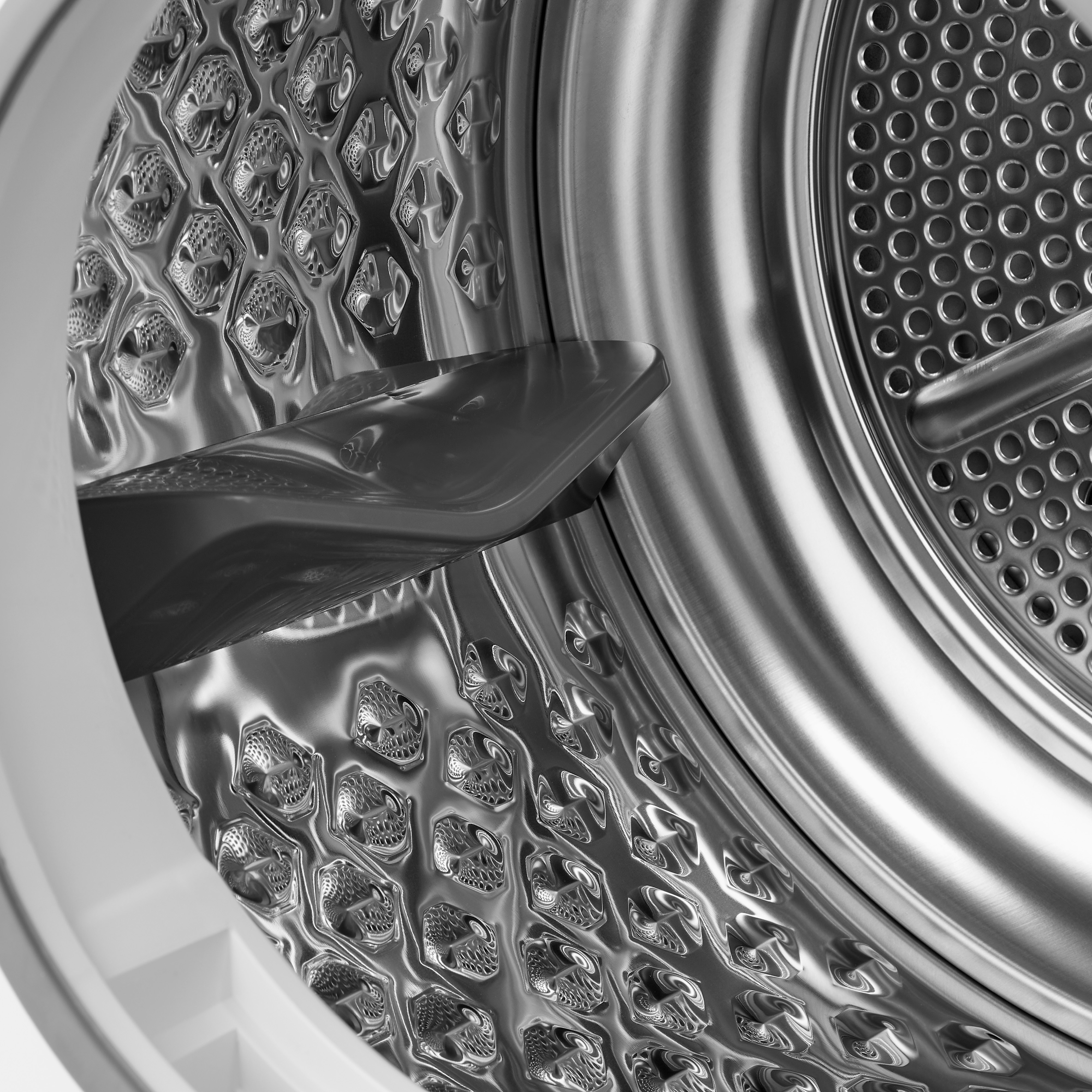 Binnenkant van een wasmachine. Het is roestvrij staal, met gaten en een schoep. De machine is leeg.