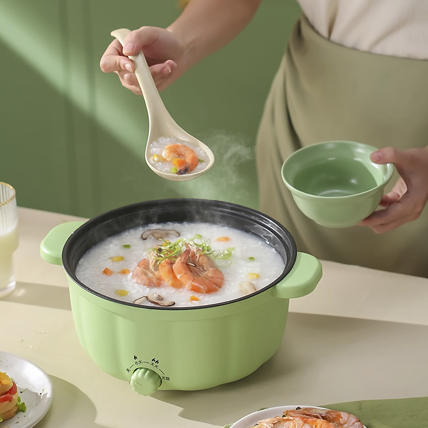 Eine Frau hält einen Löffel mit Garnelen und eine Schüssel. Ein Topf mit Garnelen-Porridge dampft.