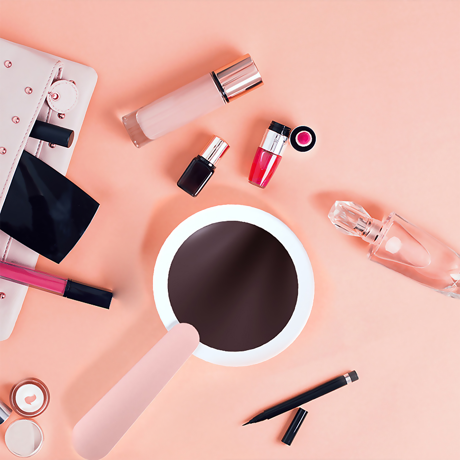 Artículos de maquillaje sobre superficie melocotón. Incluye labial, espejo, perfume.