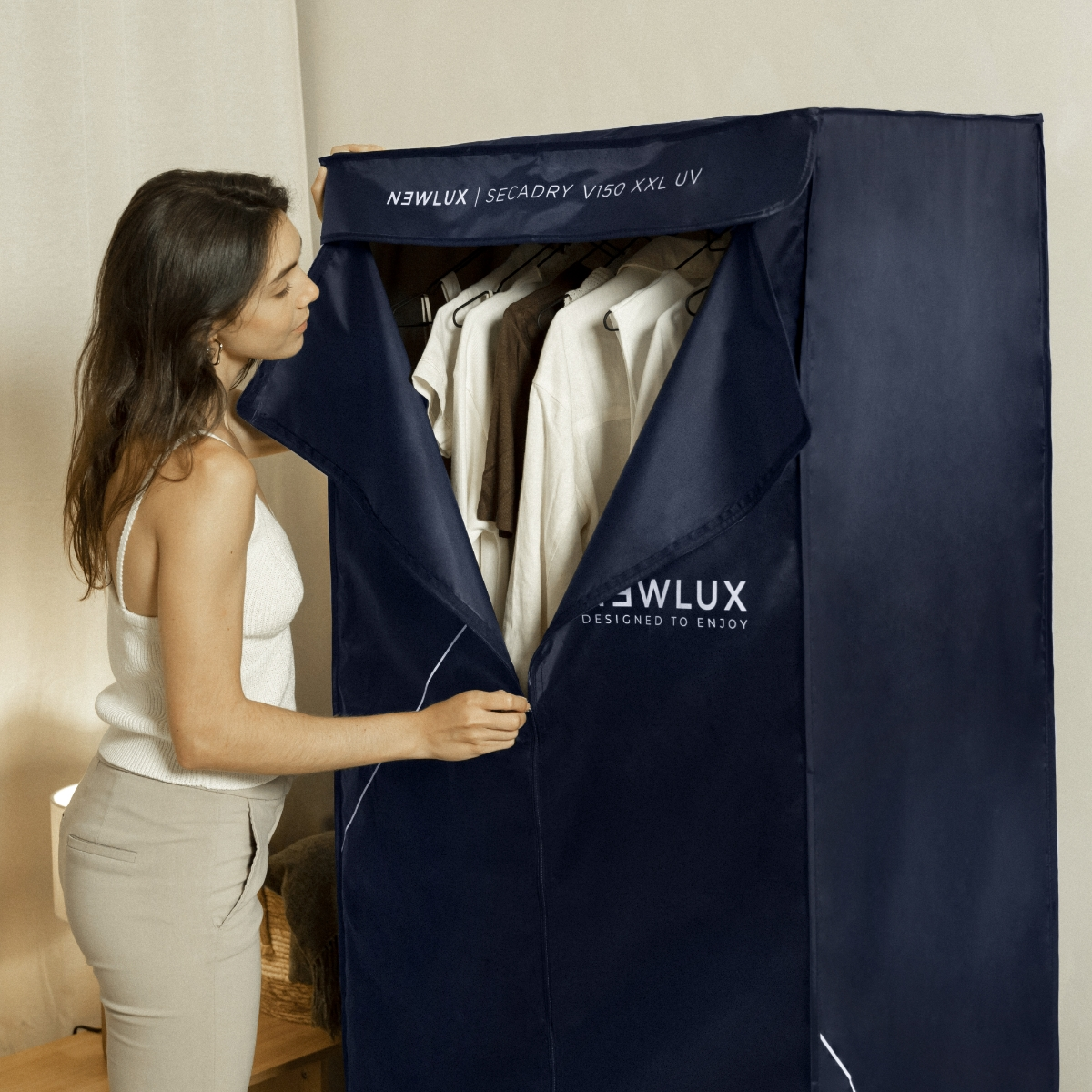 Una mujer cerrando con cremallera una bolsa de almacenamiento de ropa azul marino, mostrando la ropa dentro.