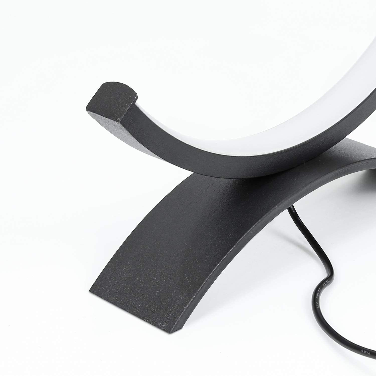 Czarny metalowy przedmiot o zakrzywionym kształcie i białym świetle na górze, na białym tle.