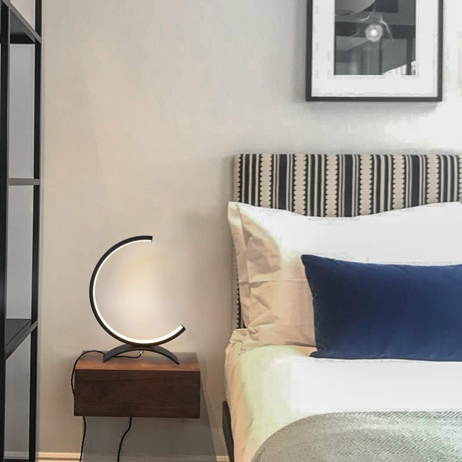 Nowoczesna czarna, łukowata lampa biurkowa na drewnianej szafce nocnej w sypialni.
