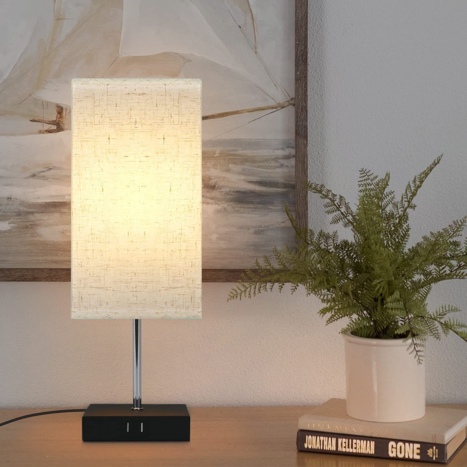 Czarna lampa z prostokątnym abażurem i czarną podstawą z portami USB. Drewniany stół.