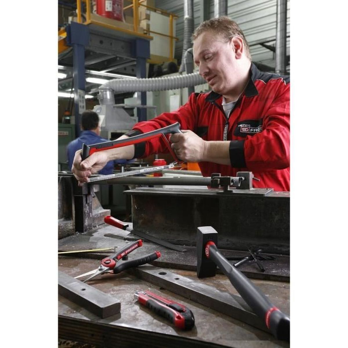 Mann benutzt Säge und Werkzeuge in Werkstatt. Metallteile und Werkzeuge auf dem Tisch.