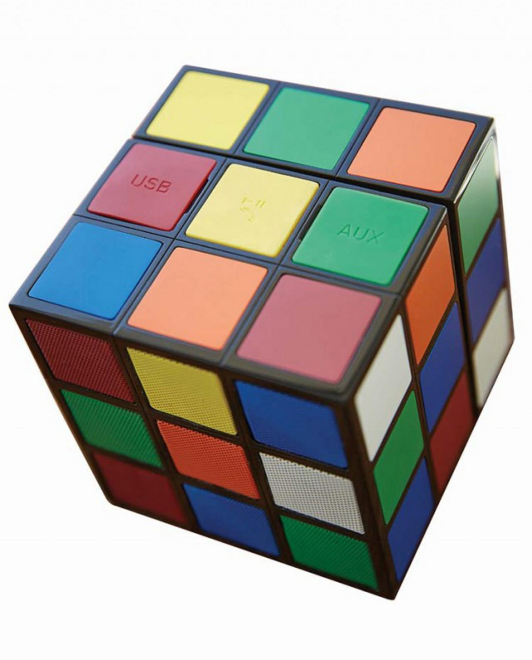 Un altoparlante a forma di cubo di Rubik multicolore con pulsanti USB, AUX e play. Su una superficie bianca.