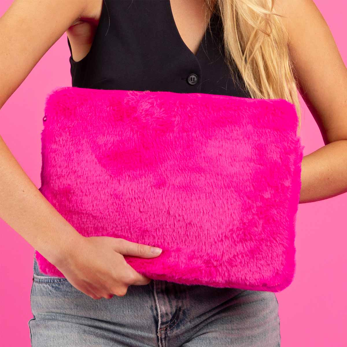 Woman holding a bright pink fluffy laptop case against a pink background.