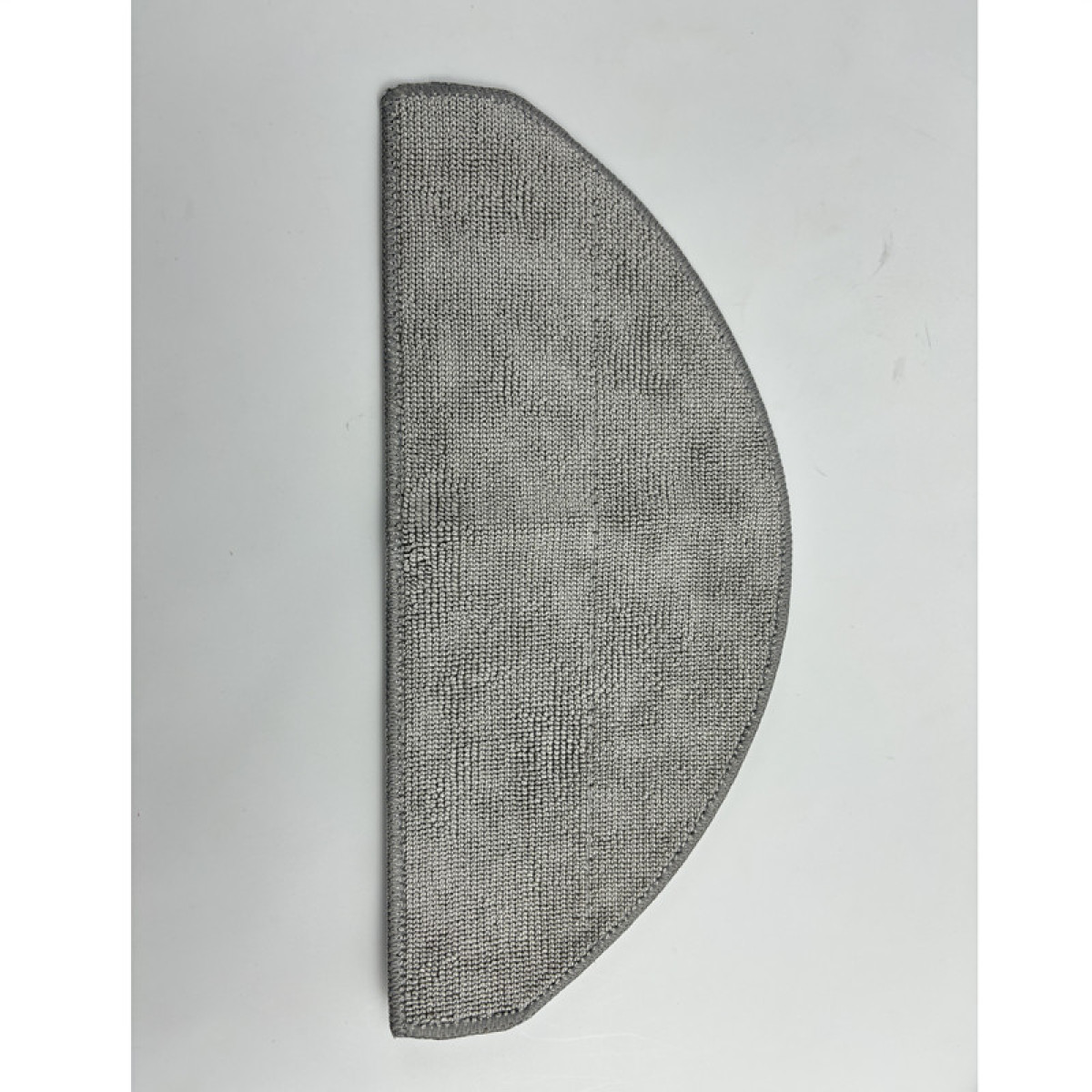 Szara mata w kształcie półokręgu na białej powierzchni. Mata jest wykonana z teksturowanej tkaniny.