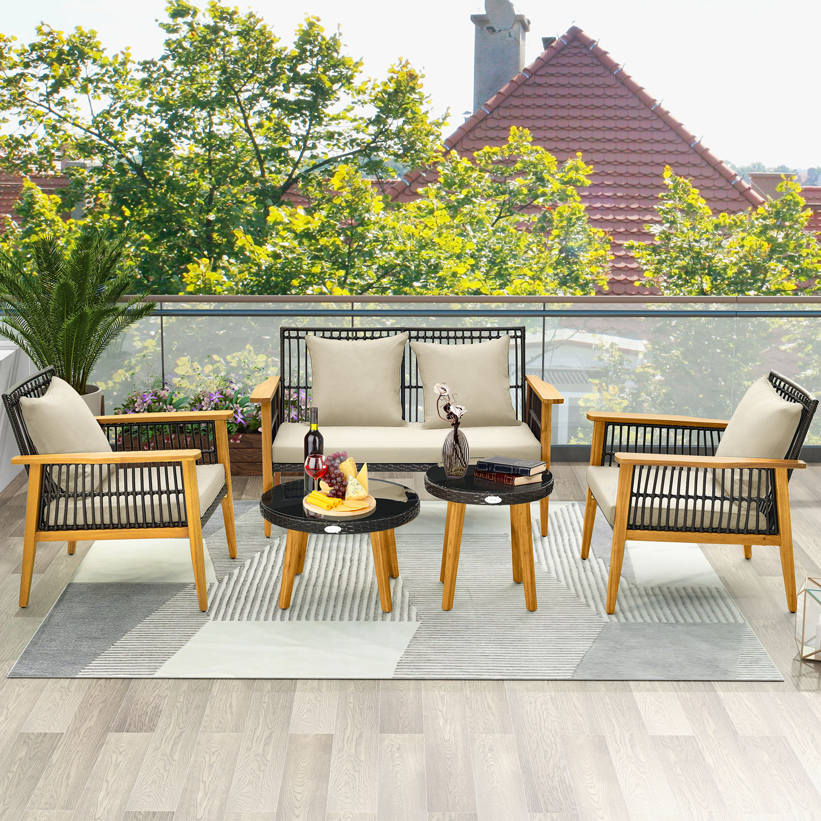 Ein Outdoor-Terrassen-Set mit einem Sofa, zwei Stühlen und zwei kleinen Tischen. Im Hintergrund befindet sich eine Baumreihe.