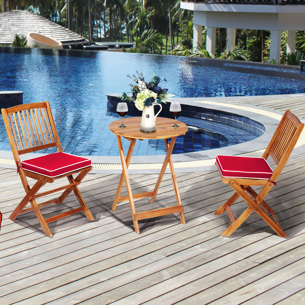 Szene am Pool mit Holztisch und Stühlen. Zwei Weingläser und Blumen auf dem Tisch.