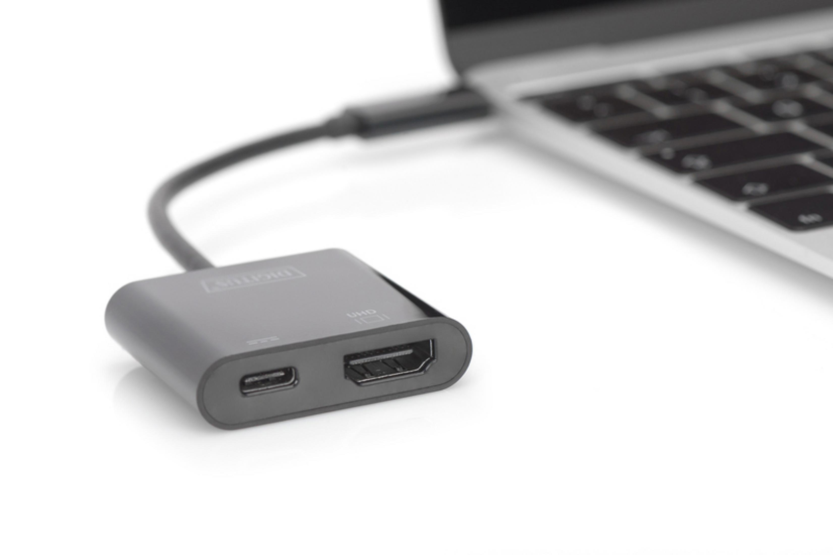 Ein grauer Adapter, der mit einem Laptop und einem HDMI-Anschluss verbunden ist.