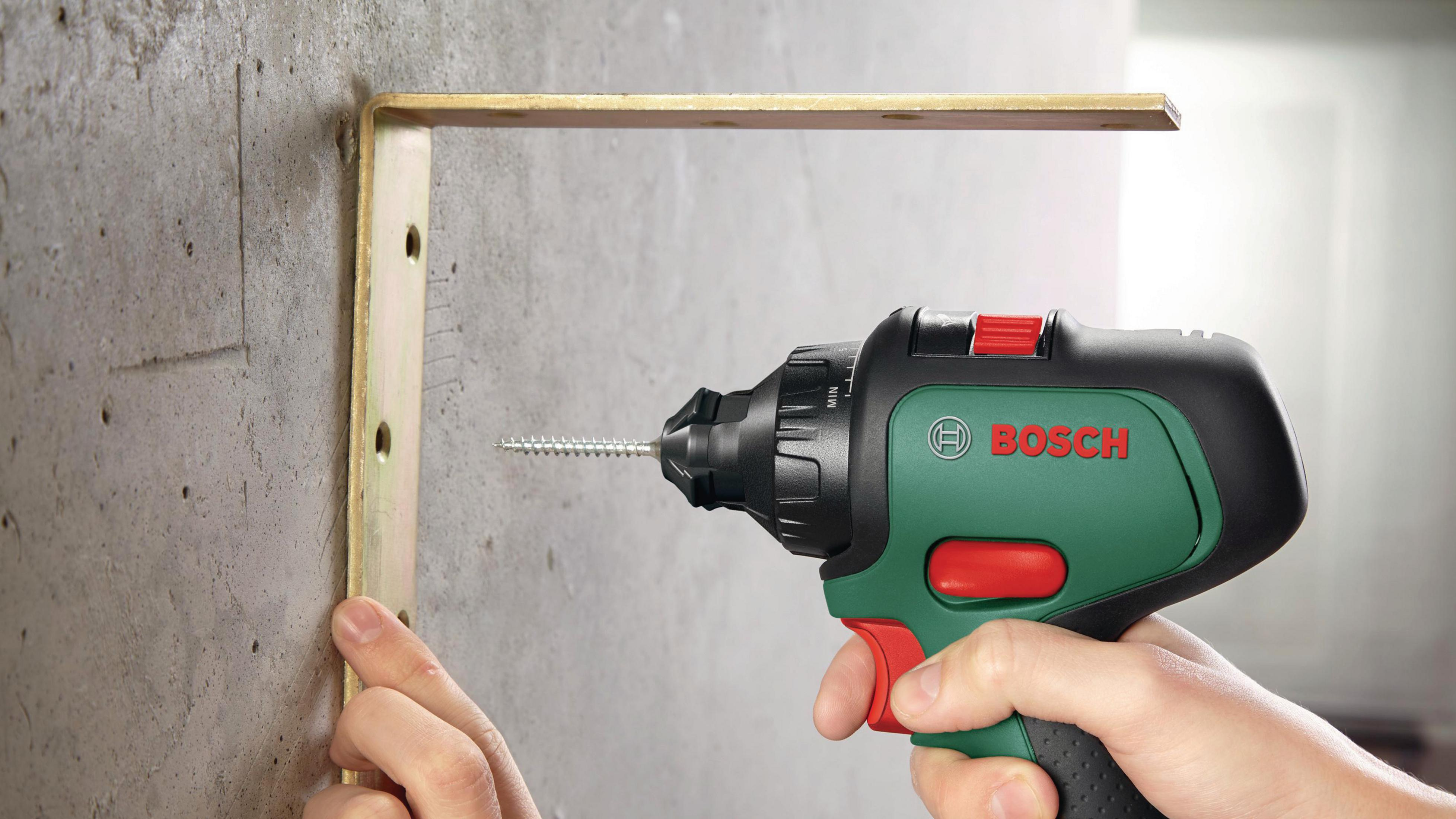 Eine Hand benutzt einen Bosch-Bohrer, um eine Halterung in eine Betonwand zu schrauben.