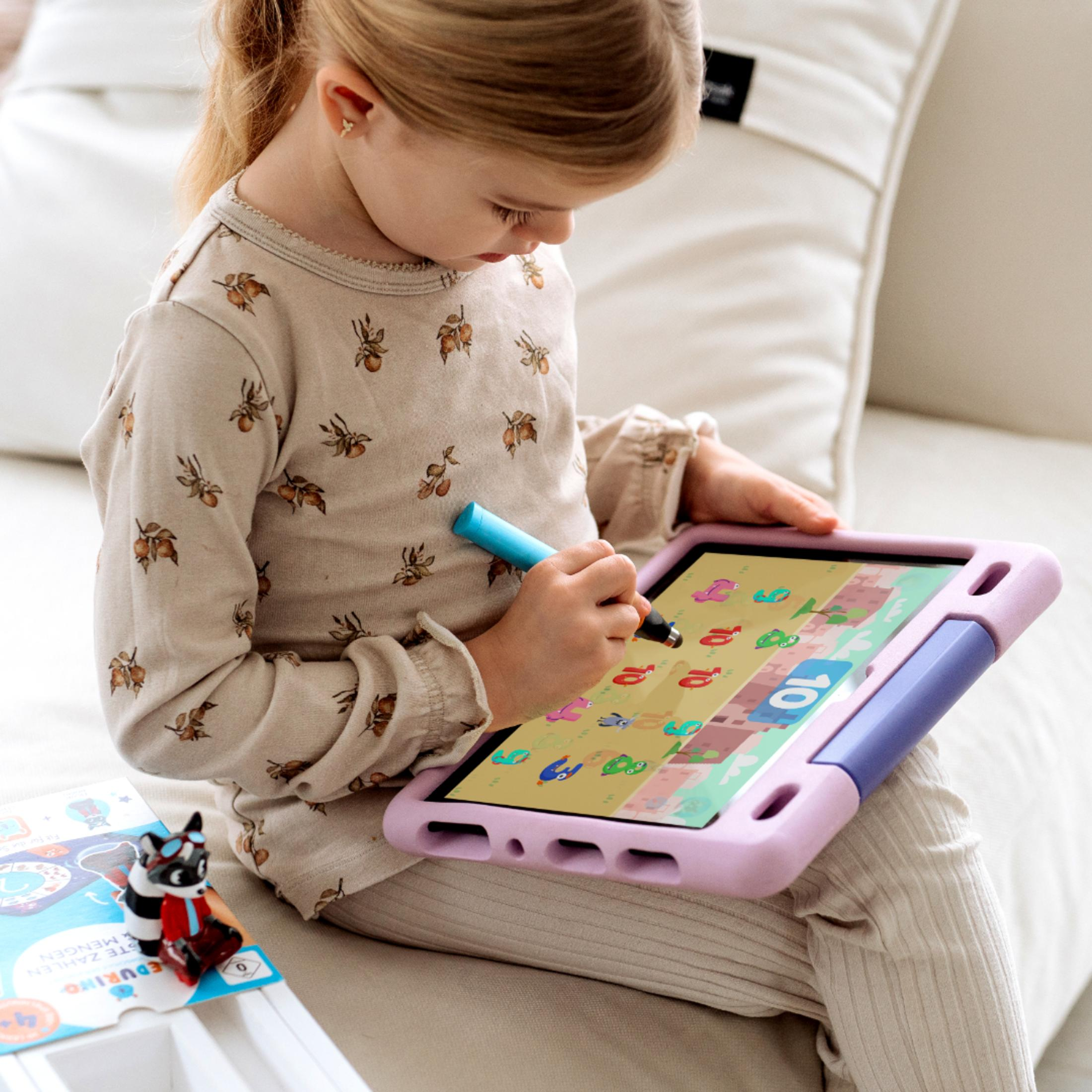 Ein junges Mädchen benutzt ein Tablet mit einem Stift. Auf einem Tisch liegen Spielzeuge und eine weiße Couch.