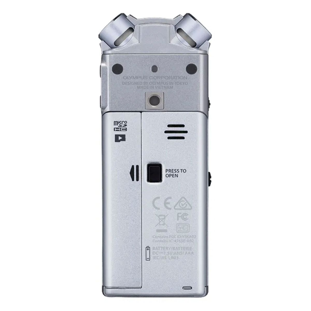 Enregistreur vocal Olympus argenté avec des boutons et un microphone. Il a un écran et un compartiment à piles.