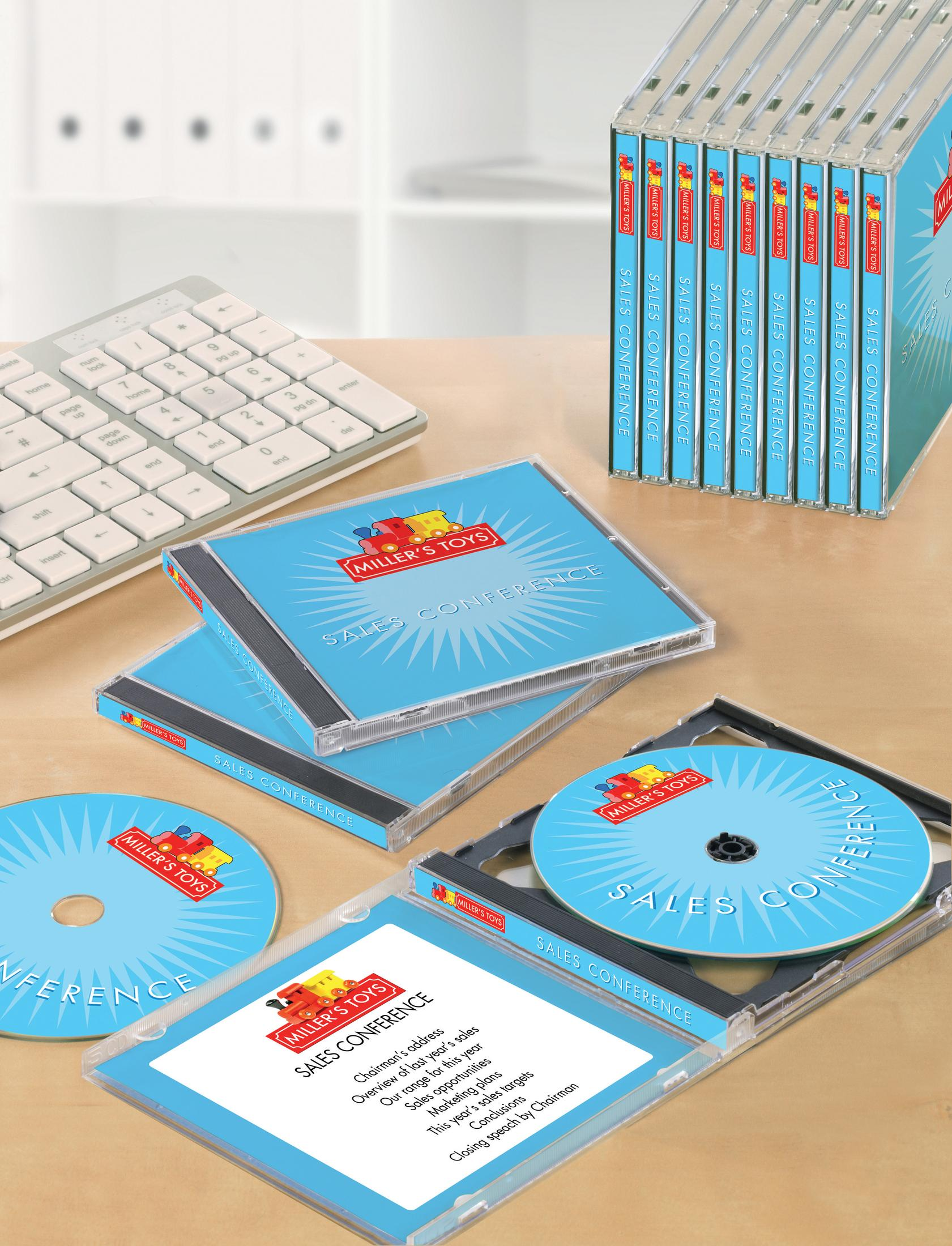 CD-Hüllen, gestapelt auf einem Schreibtisch mit Tastatur. Die CDs sind mit "Sales Conference" beschriftet.
