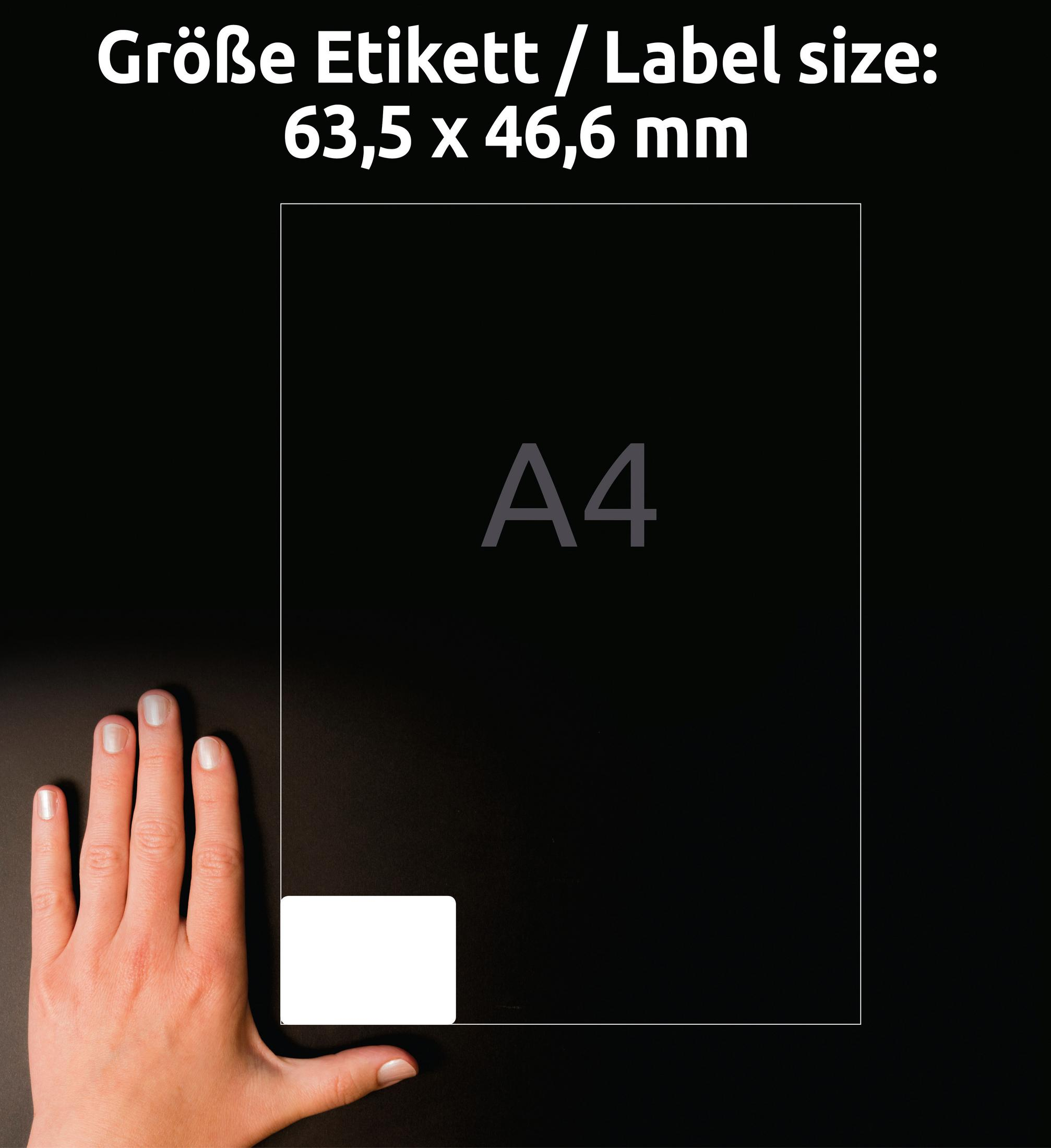 A4-Papierbogen mit Etikettengrößeninformationen und Hand auf schwarzem Hintergrund.