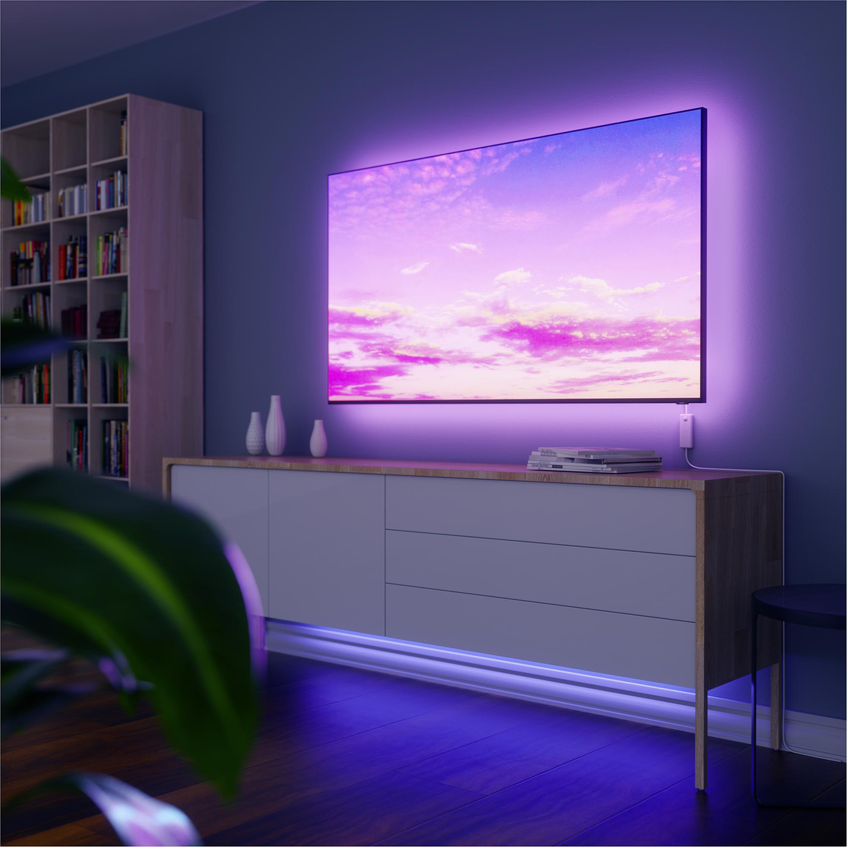Ein großer Fernseher auf einem Schrank mit Umgebungsbeleuchtung; ein violetter Schein ist vorhanden.
