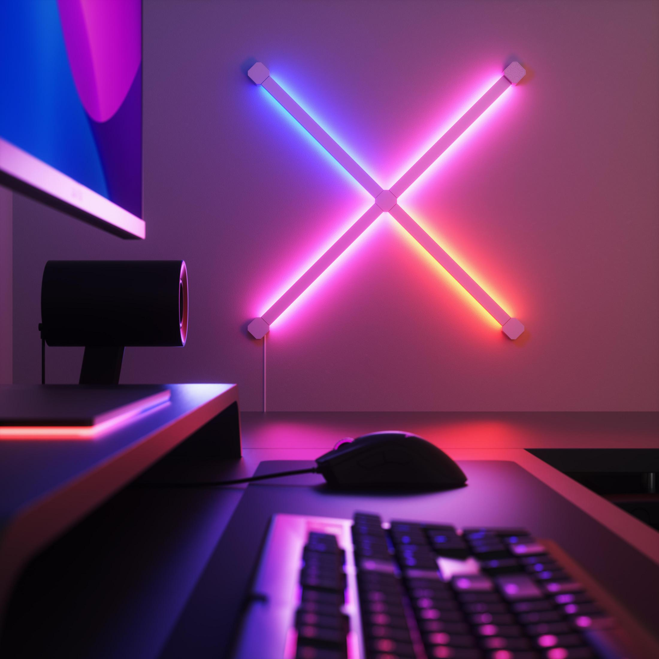 Luce al neon a forma di X su un muro. Una configurazione di computer con mouse e tastiera.