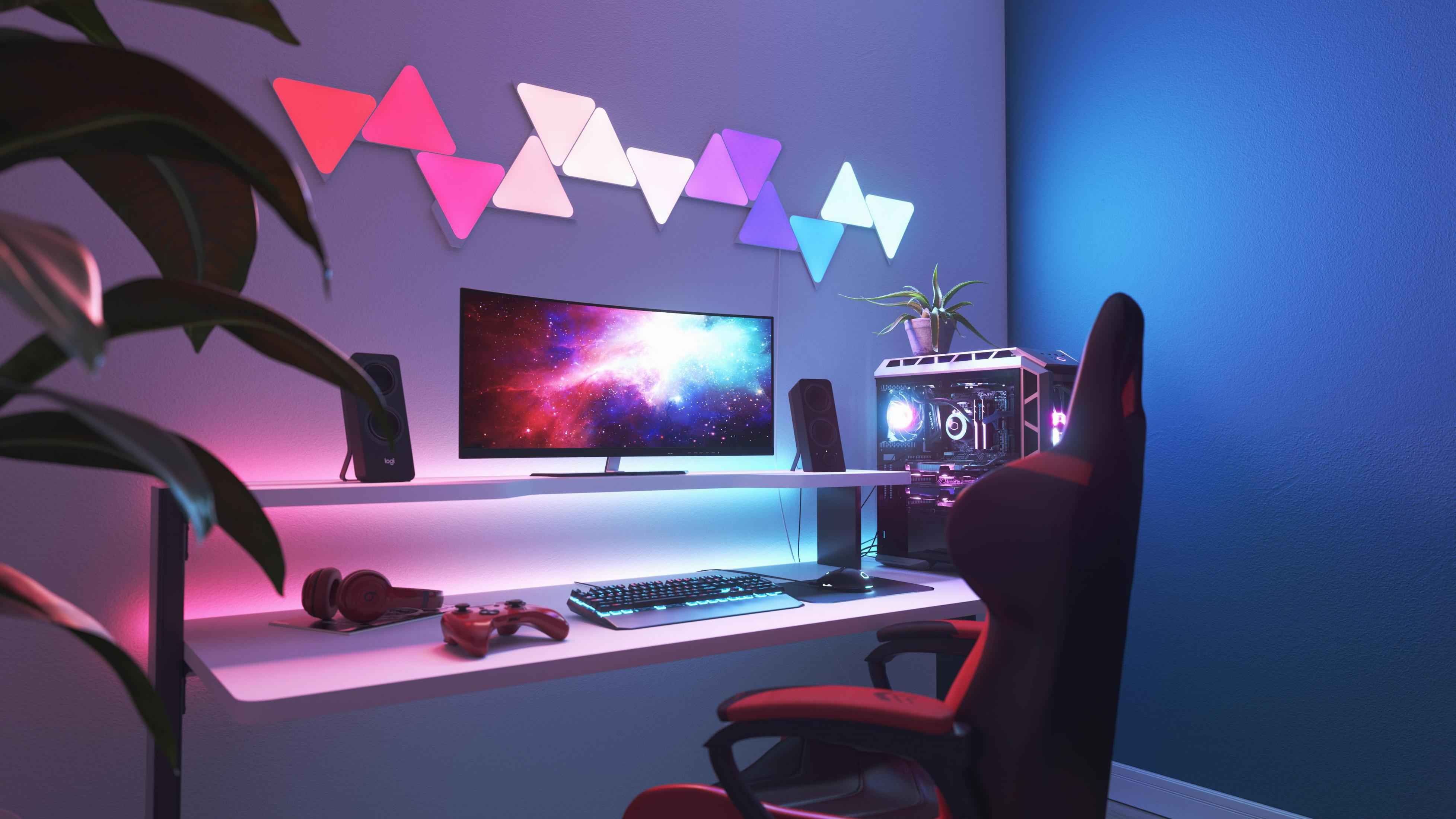 Gaming-Setup mit gebogenem Monitor, LED-Leuchten und Computer. Stuhl und Schreibtisch sind ebenfalls sichtbar.