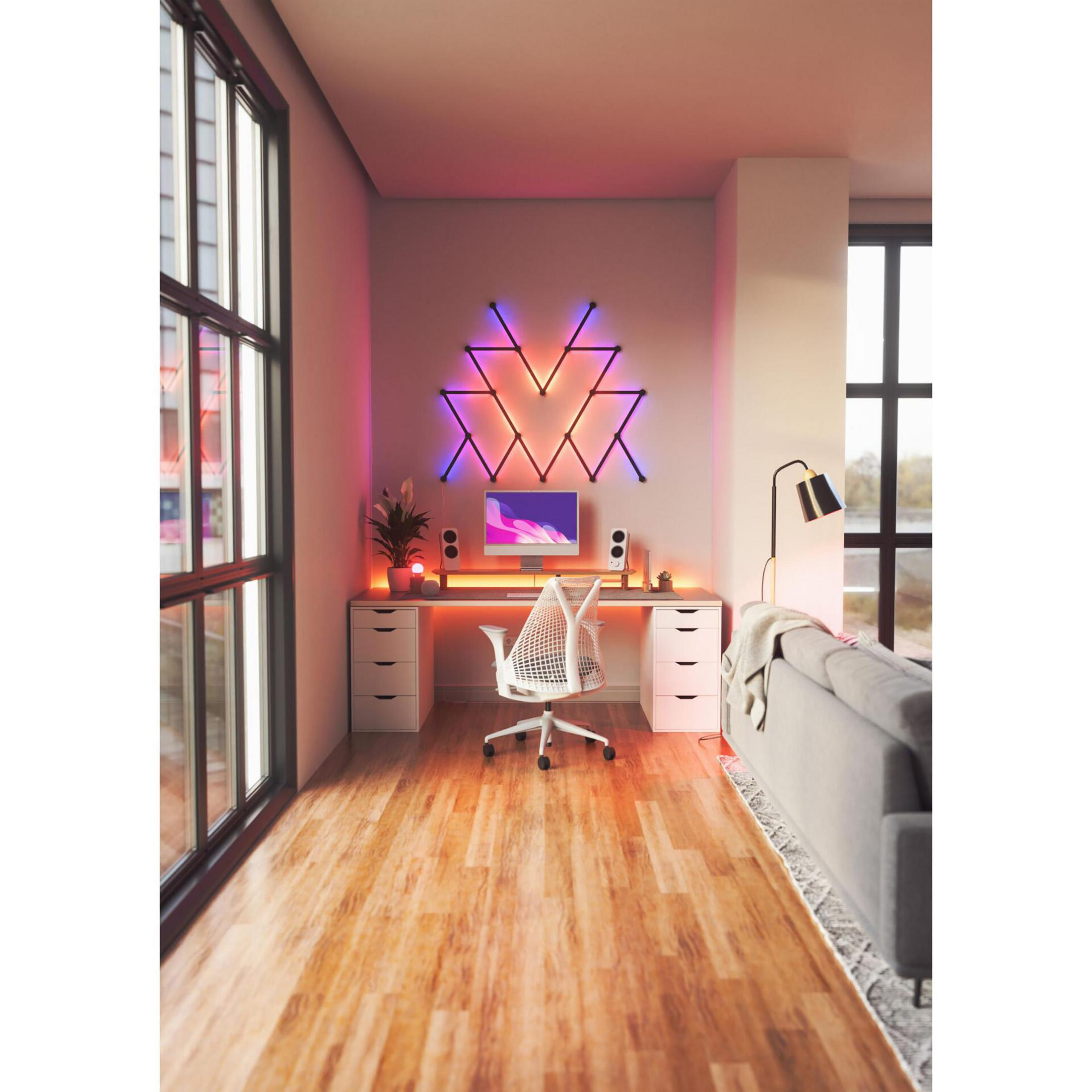 A modern home office with desk, chair, and computer. A wall decor with a geometric light fixture.