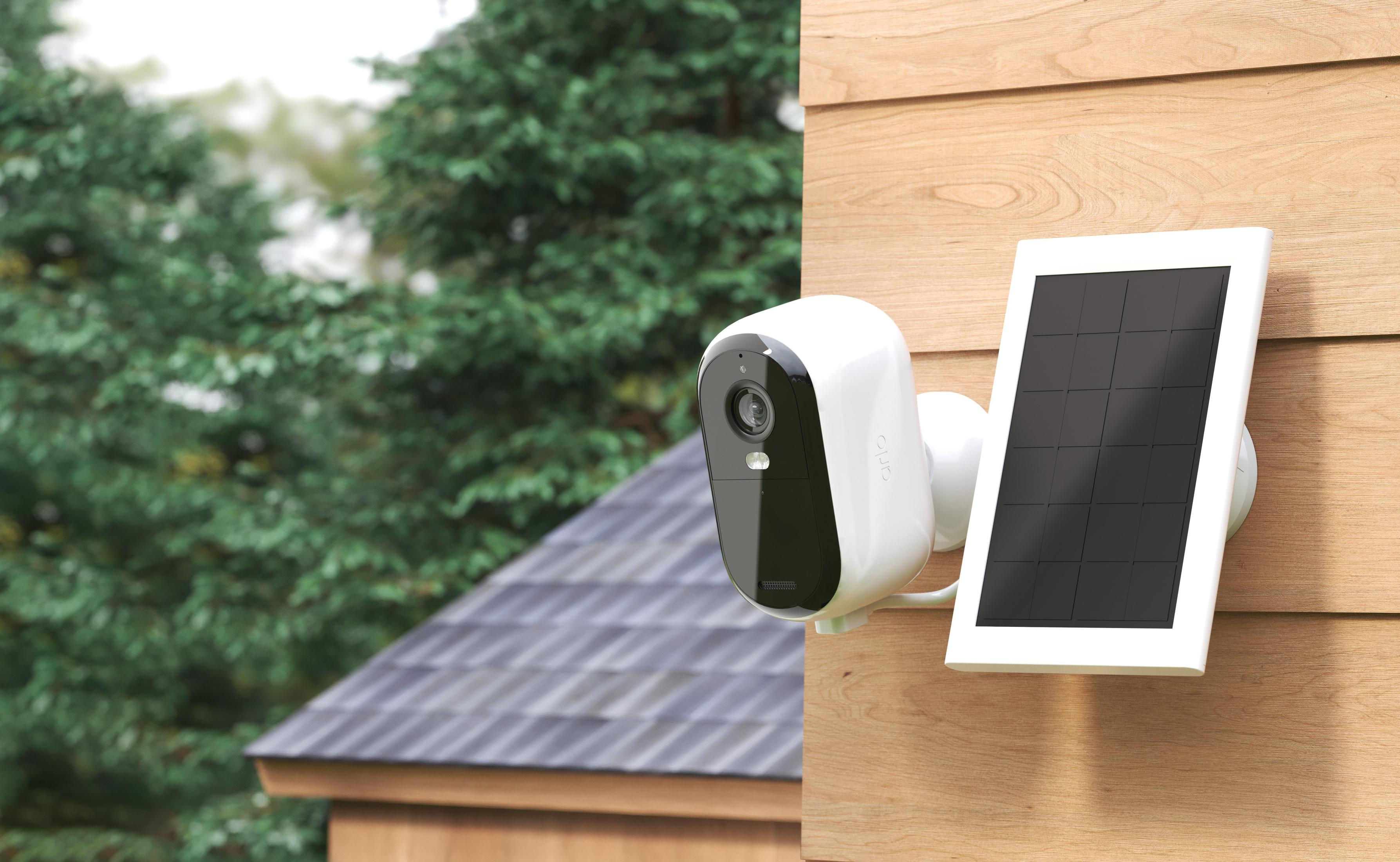 Eine weiße Überwachungskamera mit Solarpanel. Sie ist an einer Holzfassade im Freien montiert.