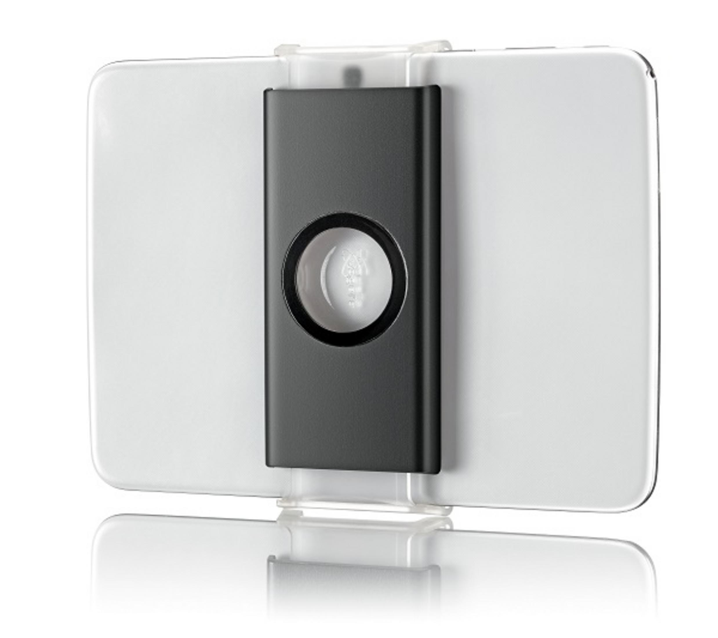 Biały tablet z czarnym elementem środkowym, prawdopodobnie podstawką. Odbija się na białej powierzchni.