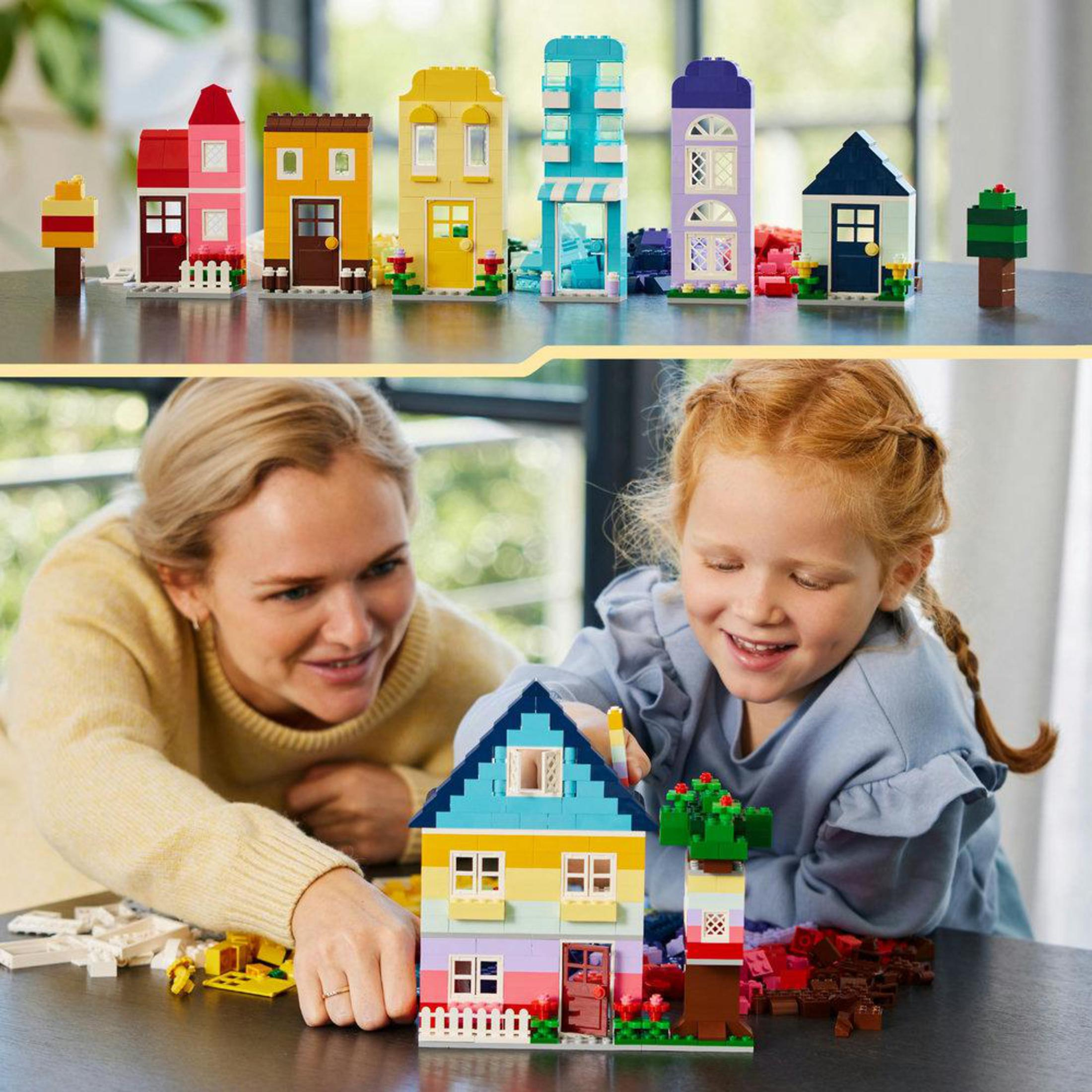 Una madre e una figlia costruiscono case con i Lego. Case Lego sullo sfondo.