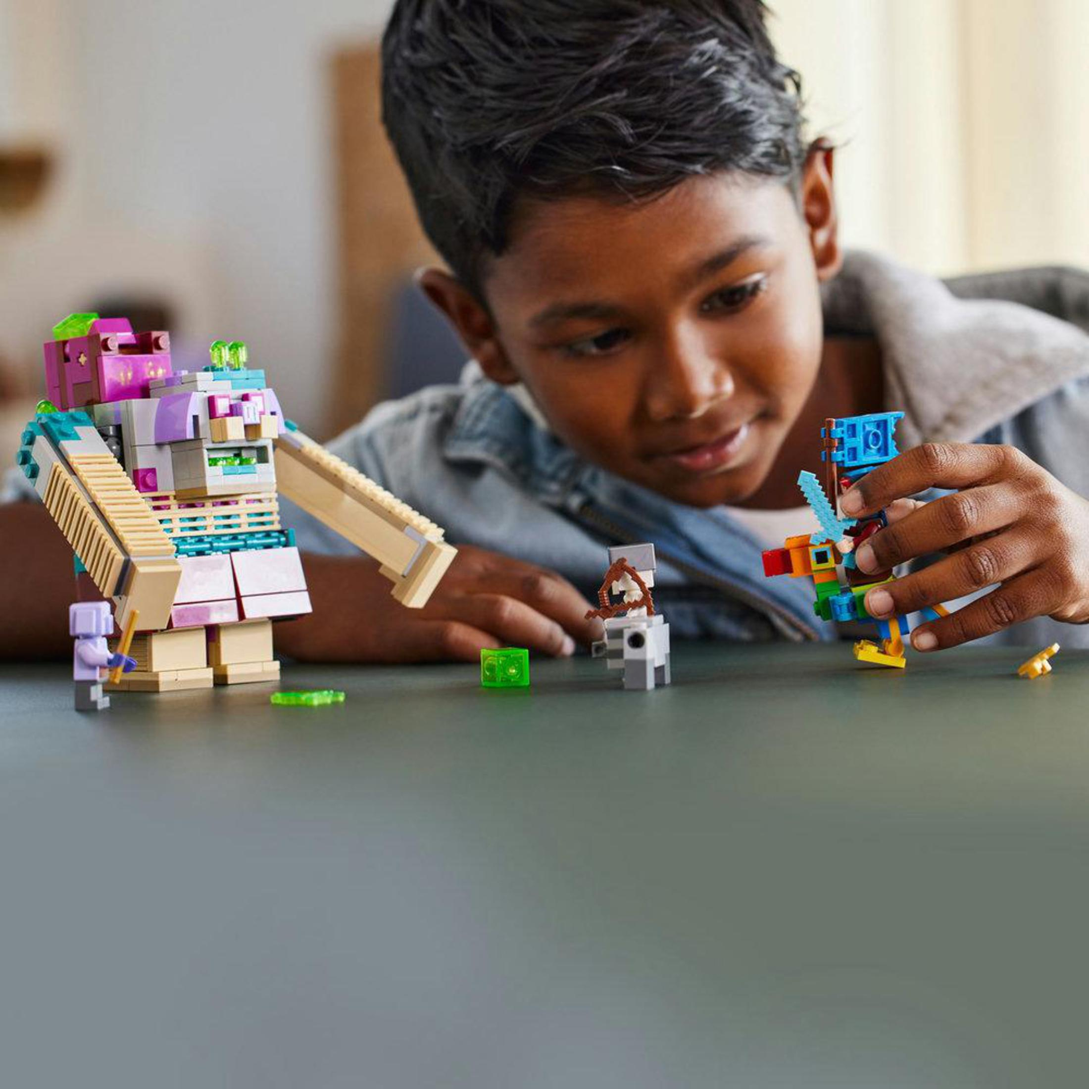 Ein Junge spielt mit Lego-Steinen. Zwei Lego-Figuren und andere Steine ​​liegen auf dem Tisch.