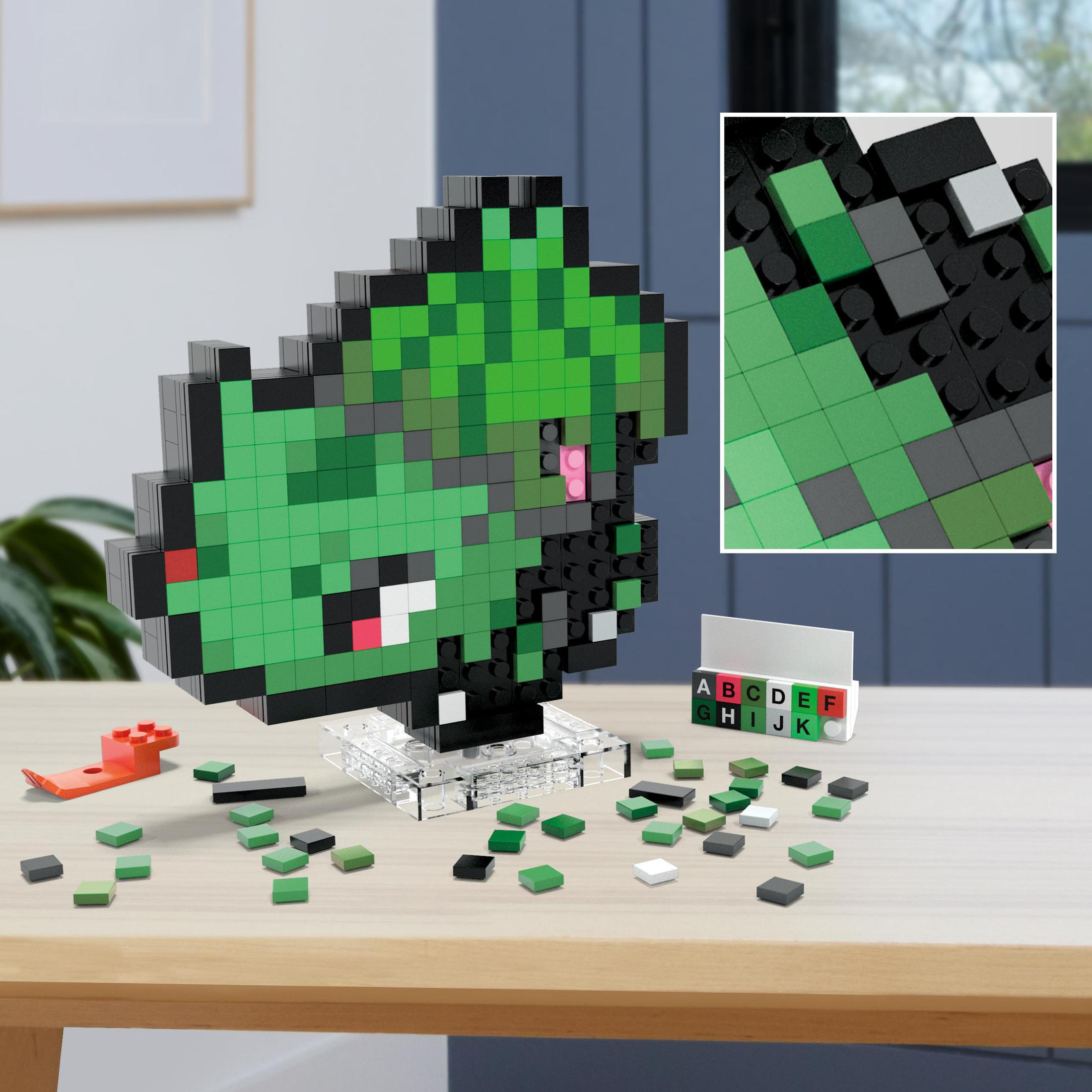 Un modello Lego di una pianta pixelata verde su un supporto, con mattoncini Lego sparsi su un tavolo di legno. Viene mostrato un primo piano.