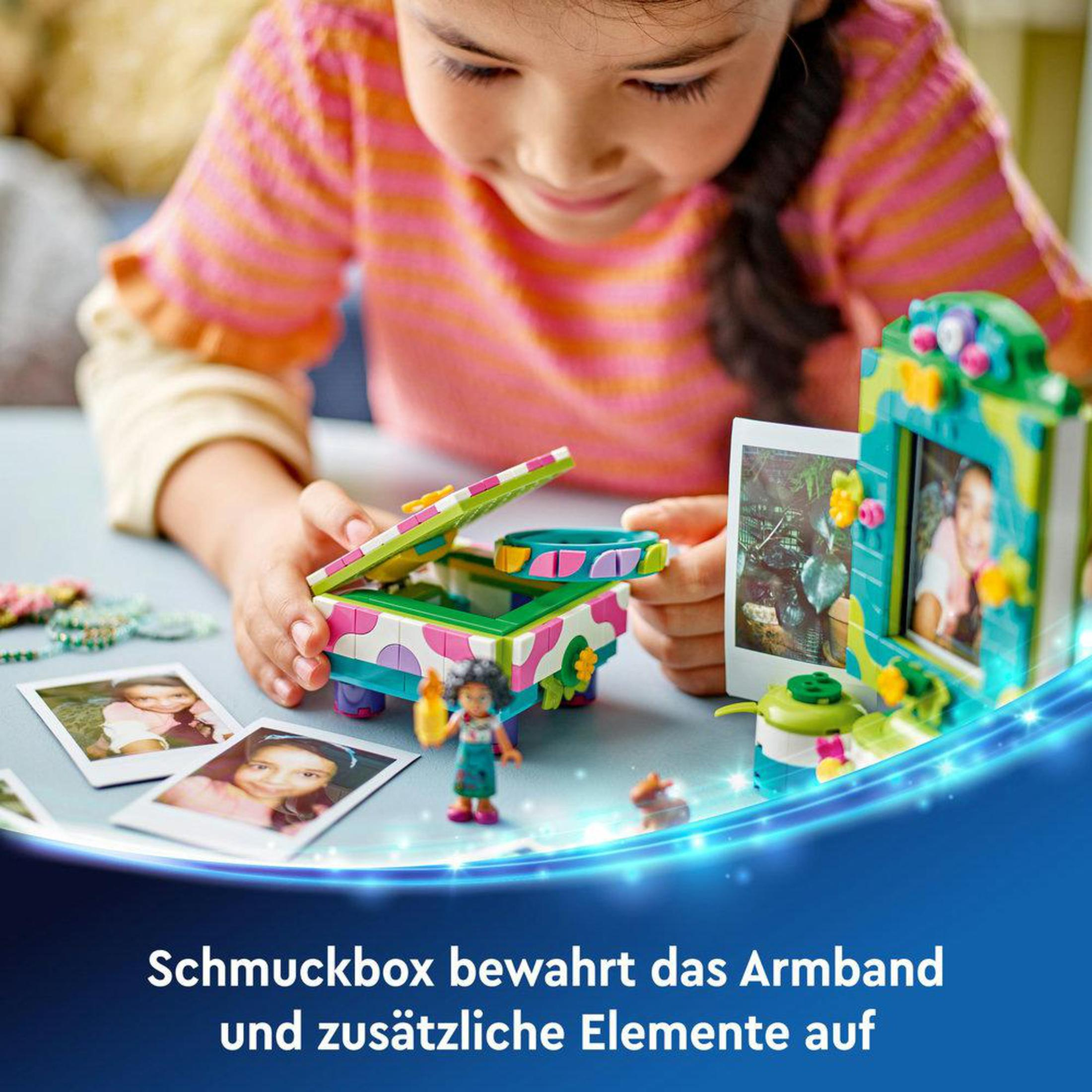 Mädchen spielt mit Spielzeug, einer Box und Fotos.