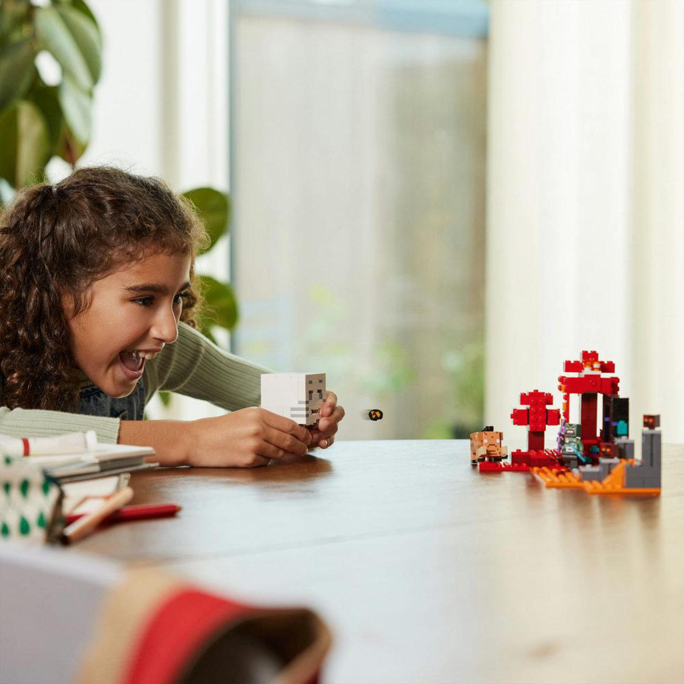 A girl looking excitedly at a Lego Minecraft scene on a table.