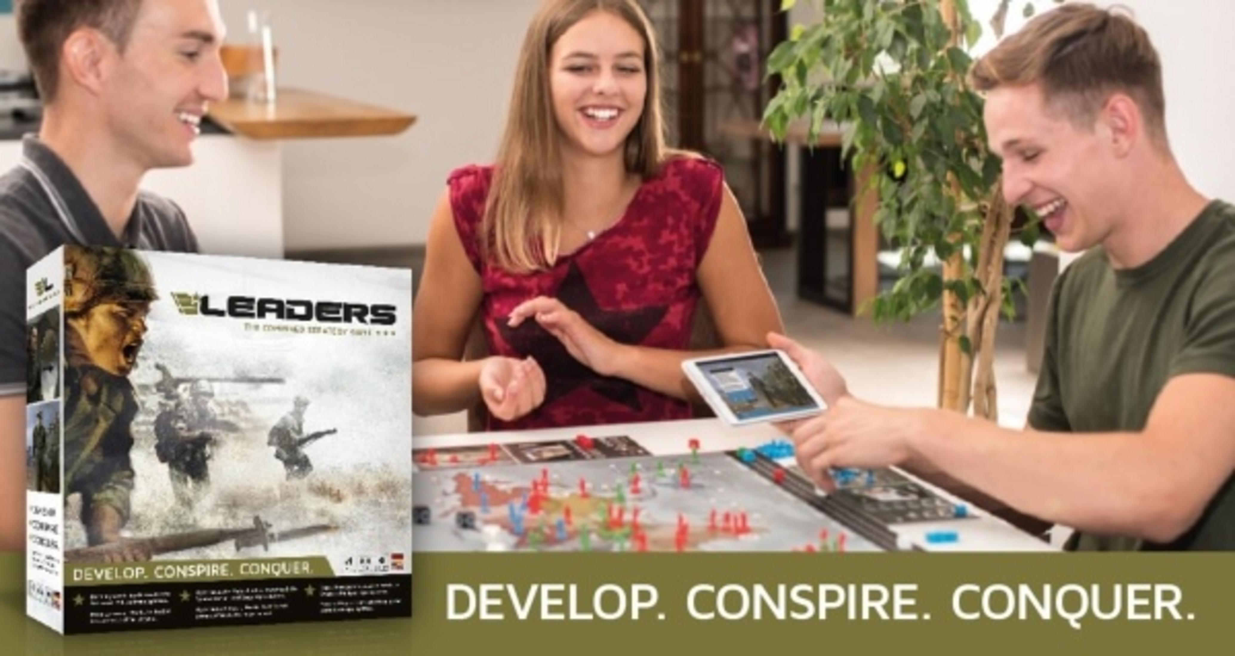 Drei Personen spielen ein Brettspiel, mit Spielbox und Tablet sichtbar.
