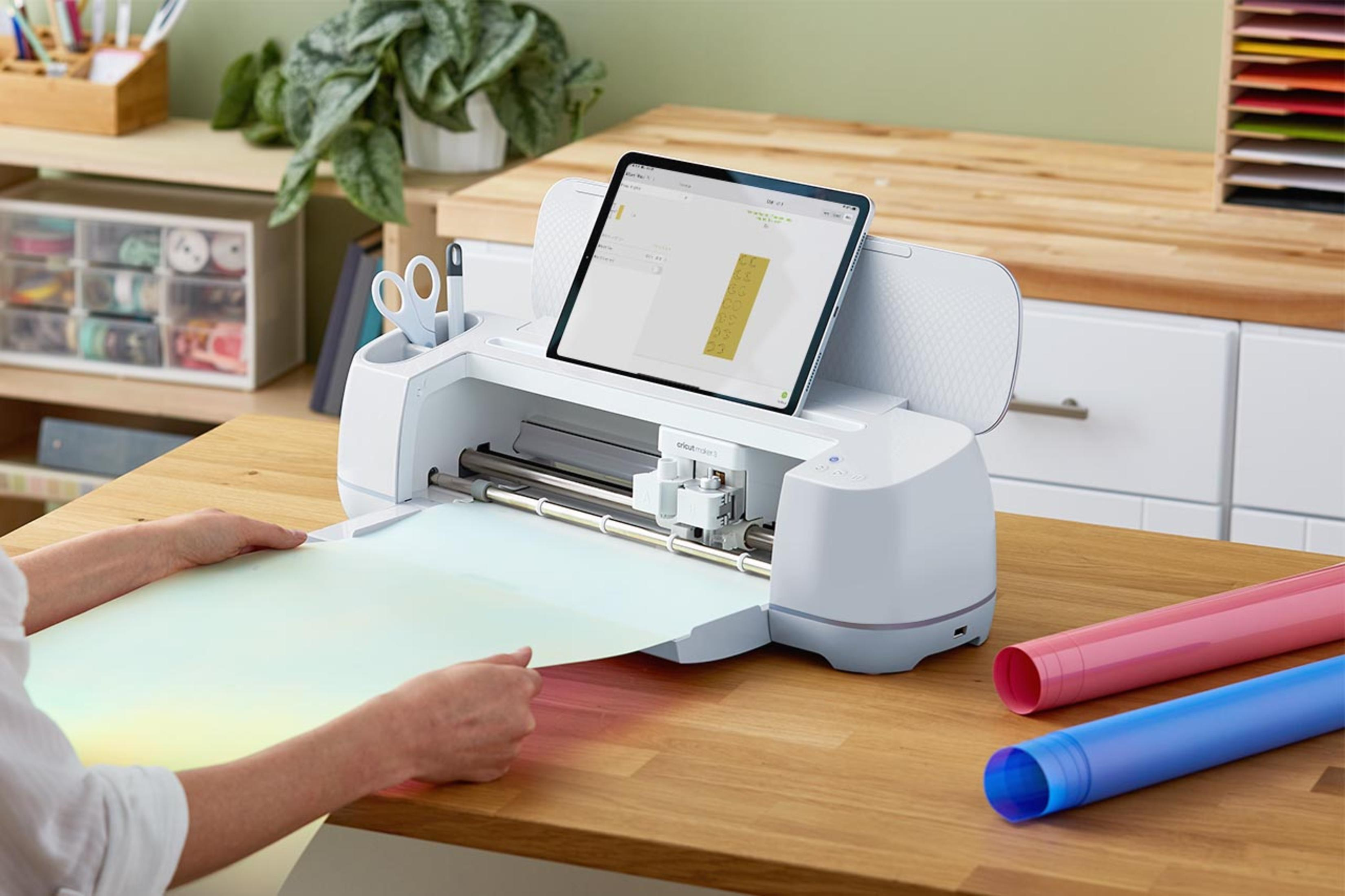 Frau, die eine Cricut-Maschine benutzt, um Material zu schneiden, mit Tablet.