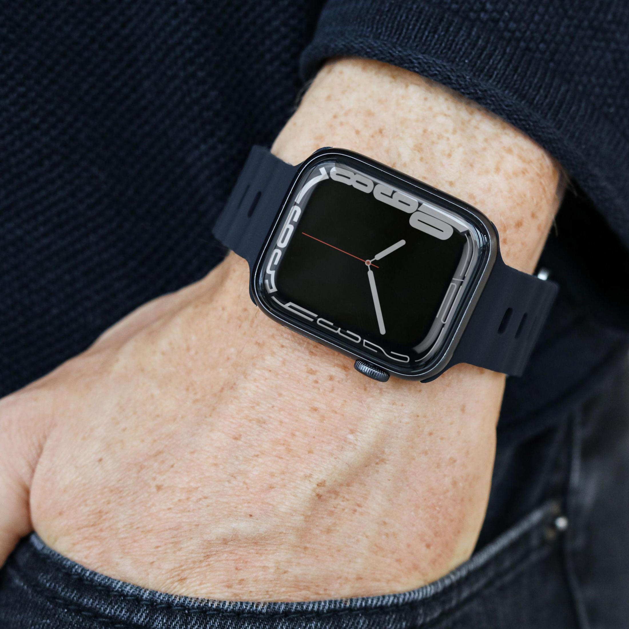Smartwatch am Handgelenk, schwarzer Bildschirm, schwarzes Band. Person trägt dunkle Kleidung. Hand im Fokus.