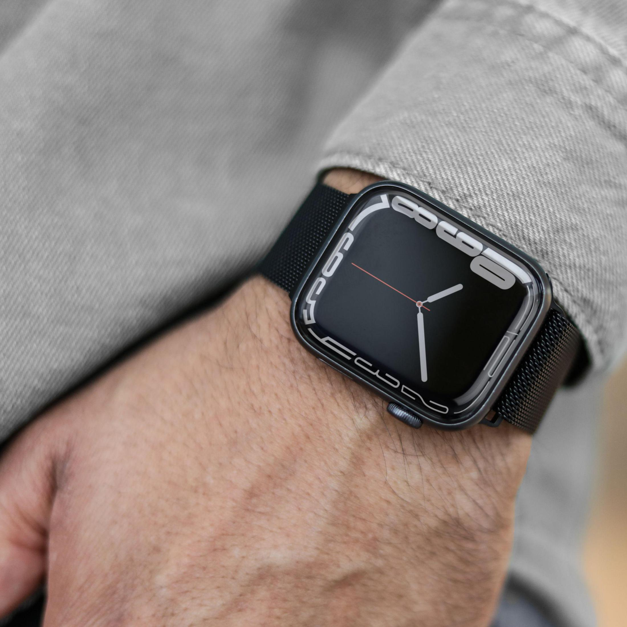 Handgelenk mit Smartwatch und schwarzem Metallarmband. Schwarzes Zifferblatt.