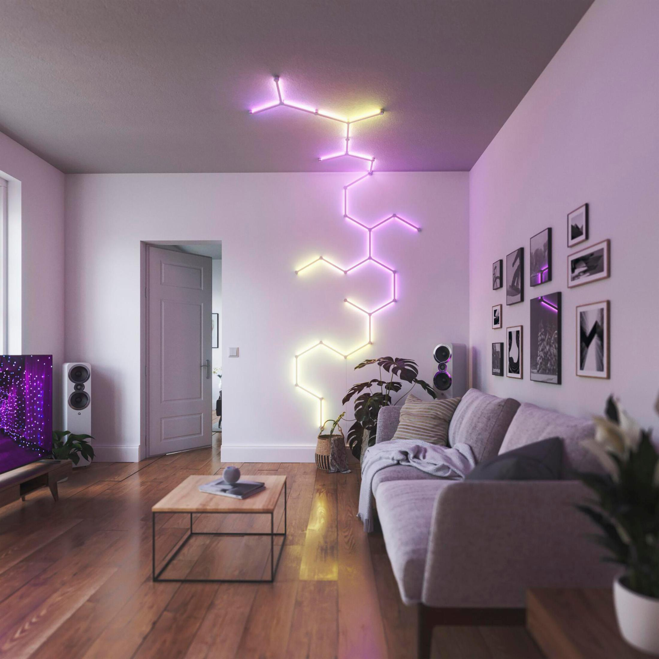 Modernes Wohnzimmer mit Sofa, Kunstwerken und farbenfrohen LED-Leuchten an der Wand.