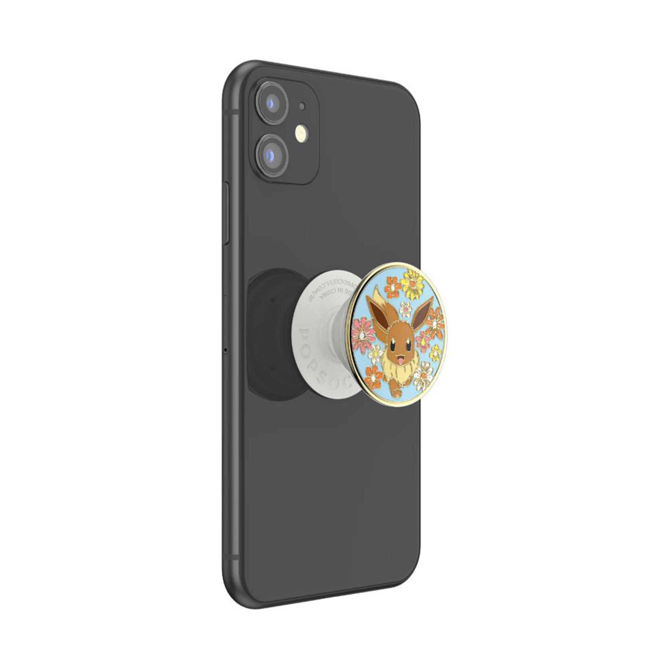 Schwarzes iPhone mit PopSocket mit Evoli, umgeben von Blumen.