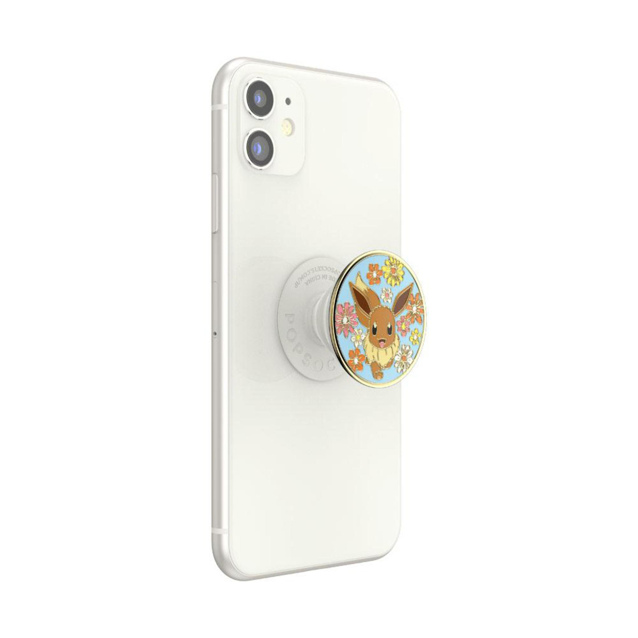 Weißes iPhone mit PopSocket mit Evoli, umgeben von Blumen.
