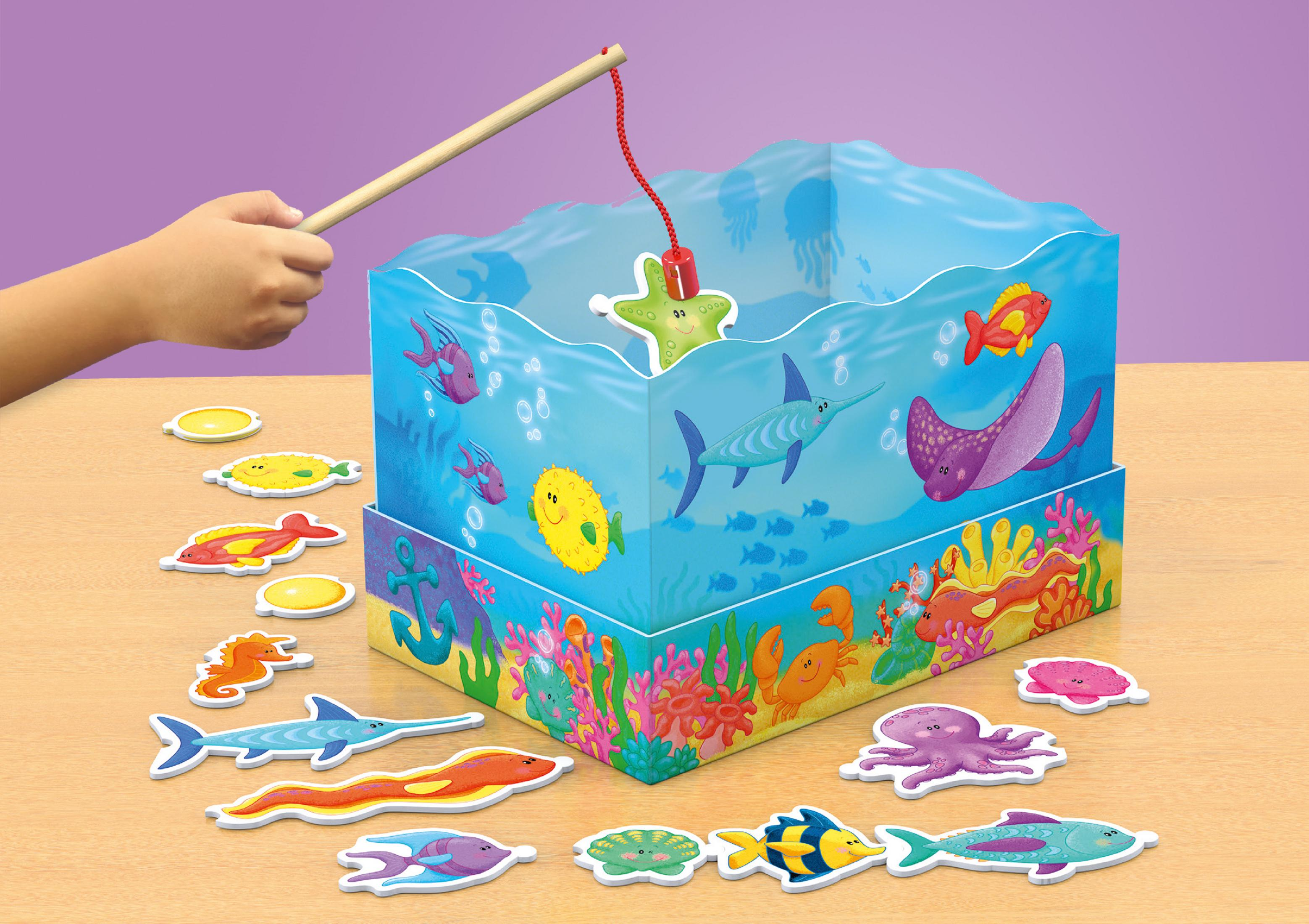 Ręka dziecka łowiąca drewnianą wędką z zabawkowego akwarium. Zabawki ryb są rozrzucone.