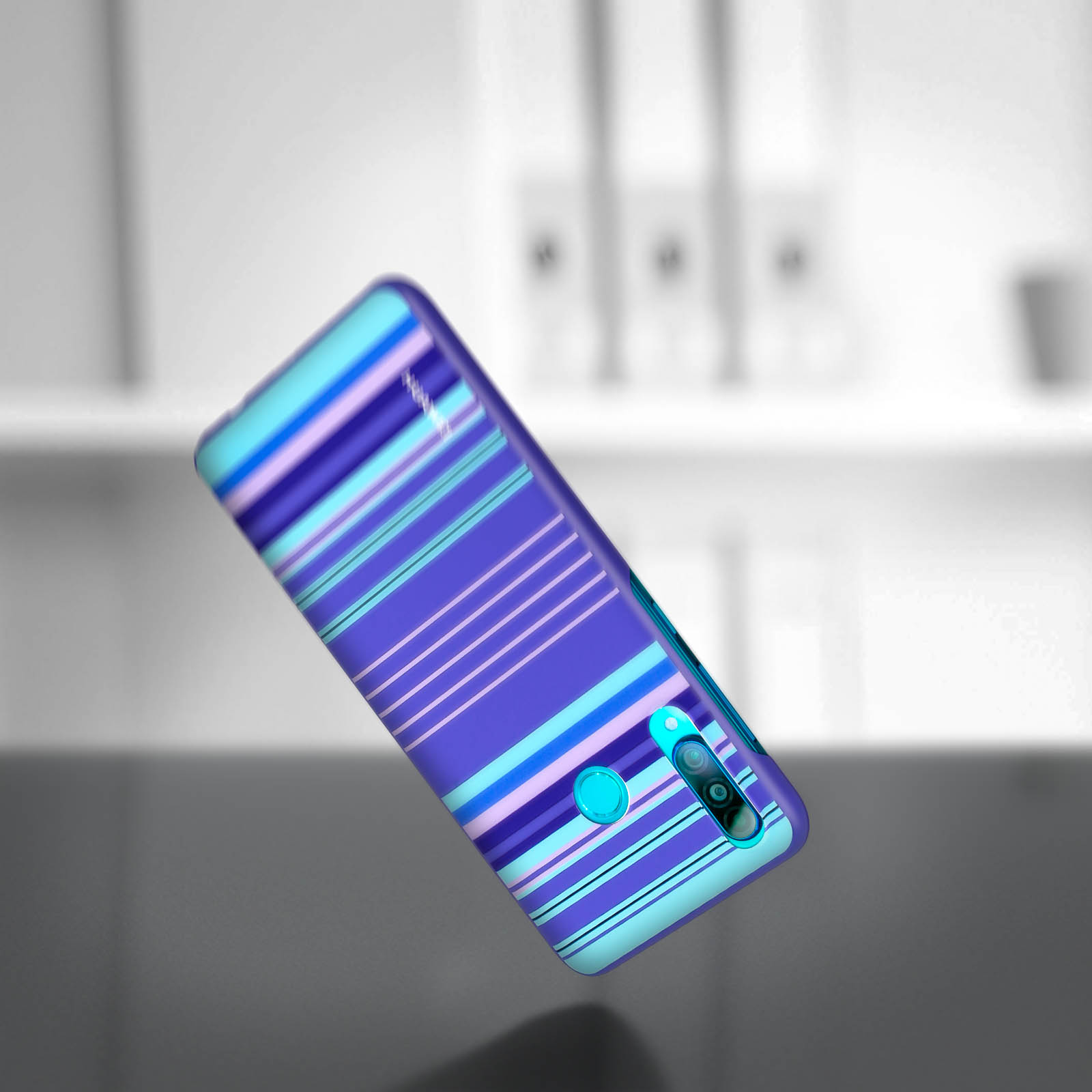 Custodia per telefono con strisce blu e viola. Il telefono è in aria, ad angolo, su una superficie grigia.