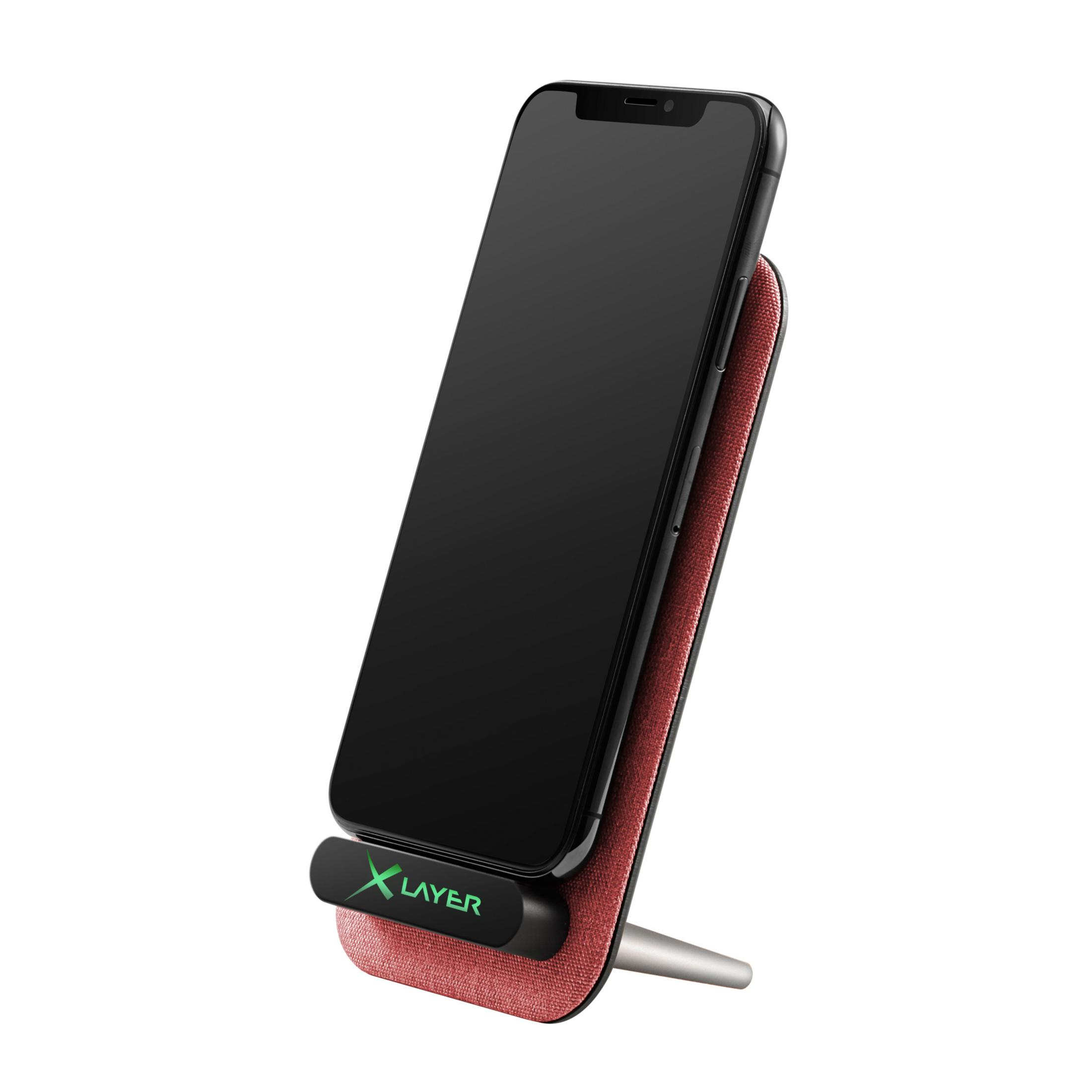 Ein Telefon liegt auf einem roten und schwarzen kabellosen Ladegerät mit dem Logo 'X Layer'.