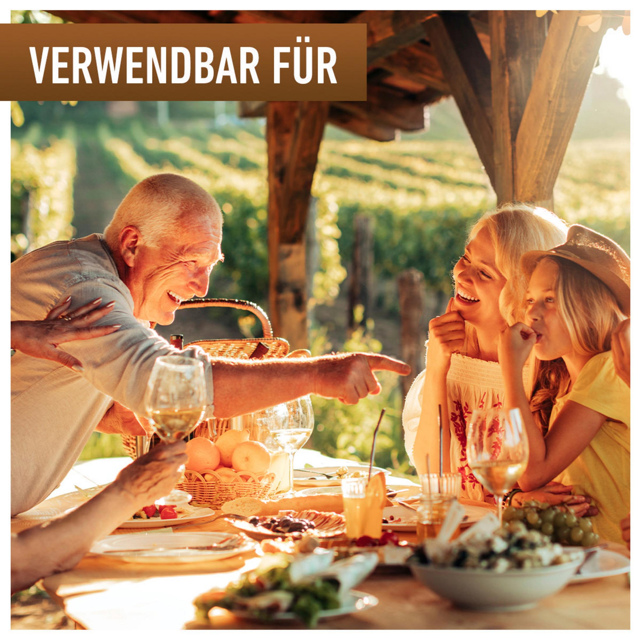 Rodzina je i śmieje się na zewnątrz; kieliszki do wina i jedzenie na stole.